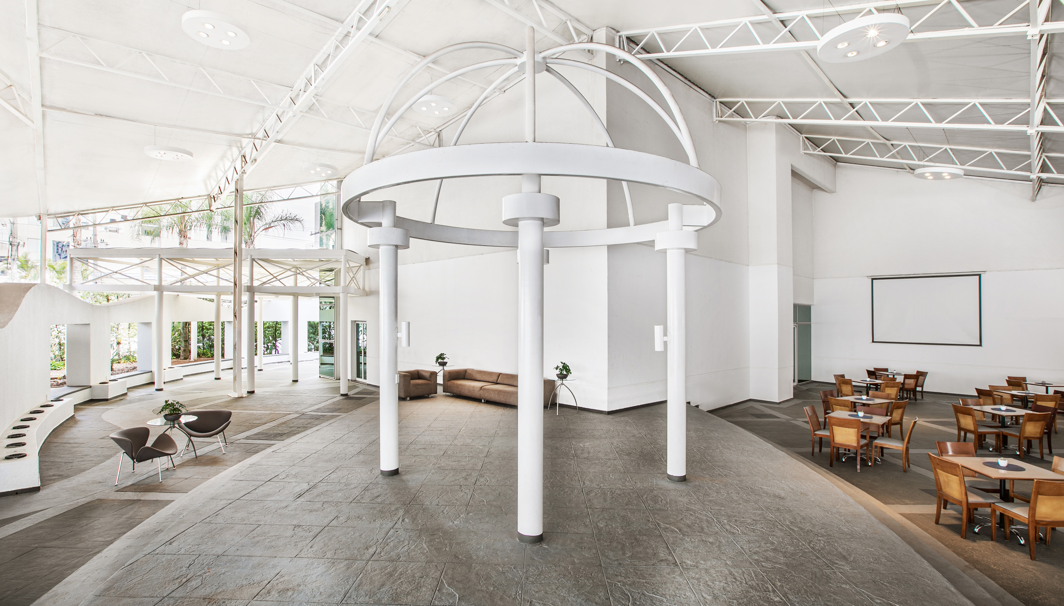 Modern white lobby with circular centerpiece, lounge, and cafe seating areas.