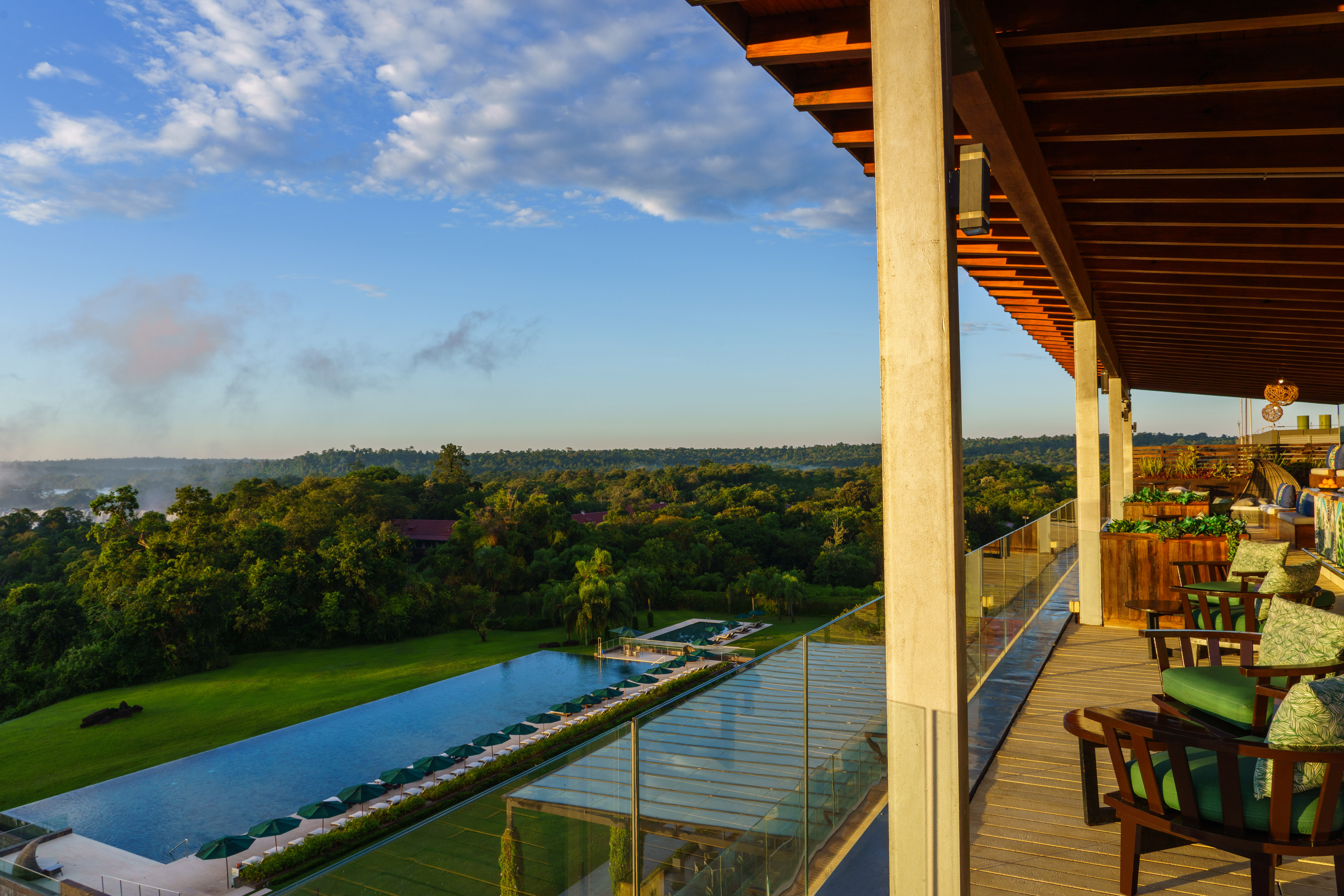 Luxury resort patio, infinity pool, rainforest, and distant Iguazu Falls.