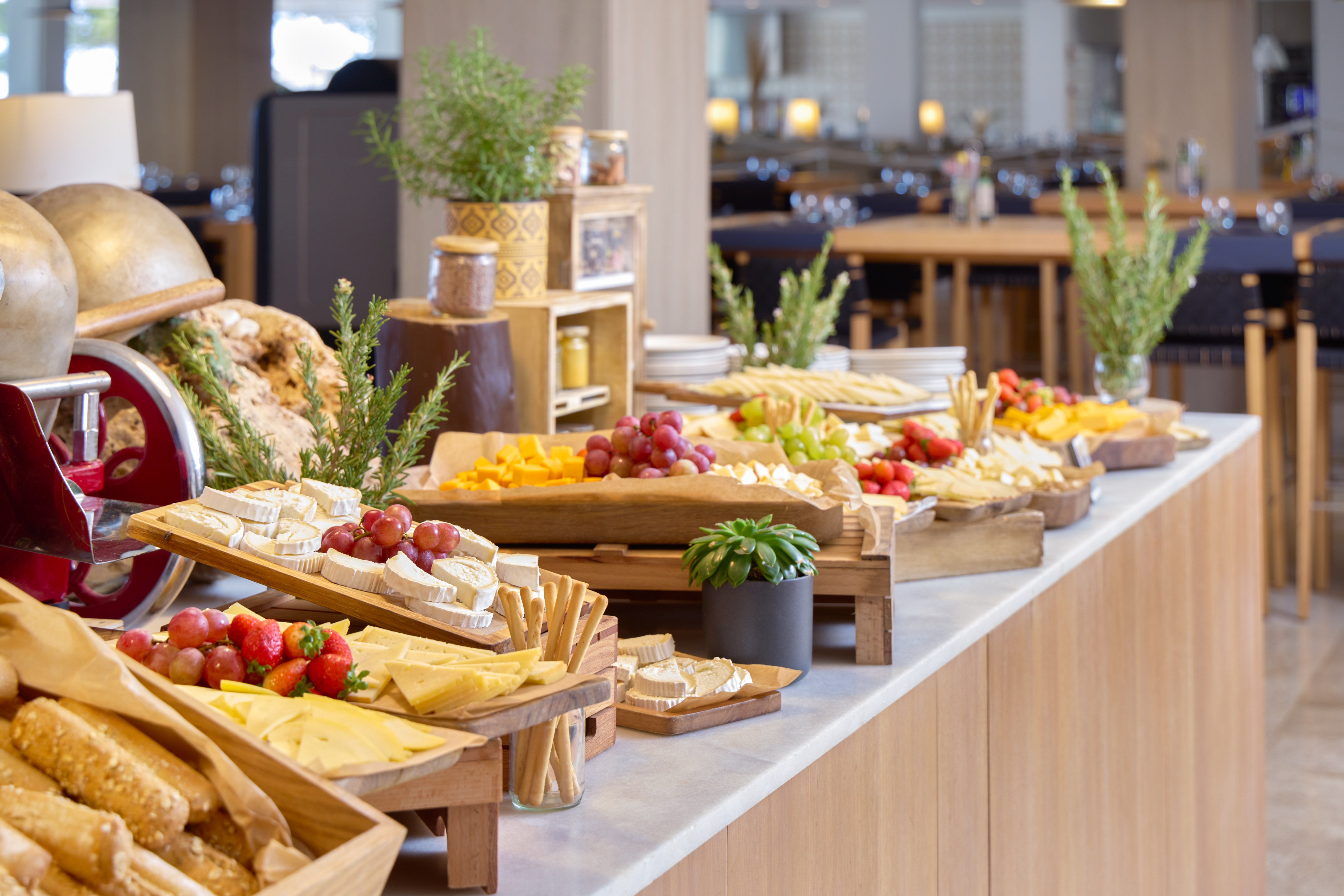 Buffet spread with assorted cheeses, fresh grapes, strawberries, and bread.