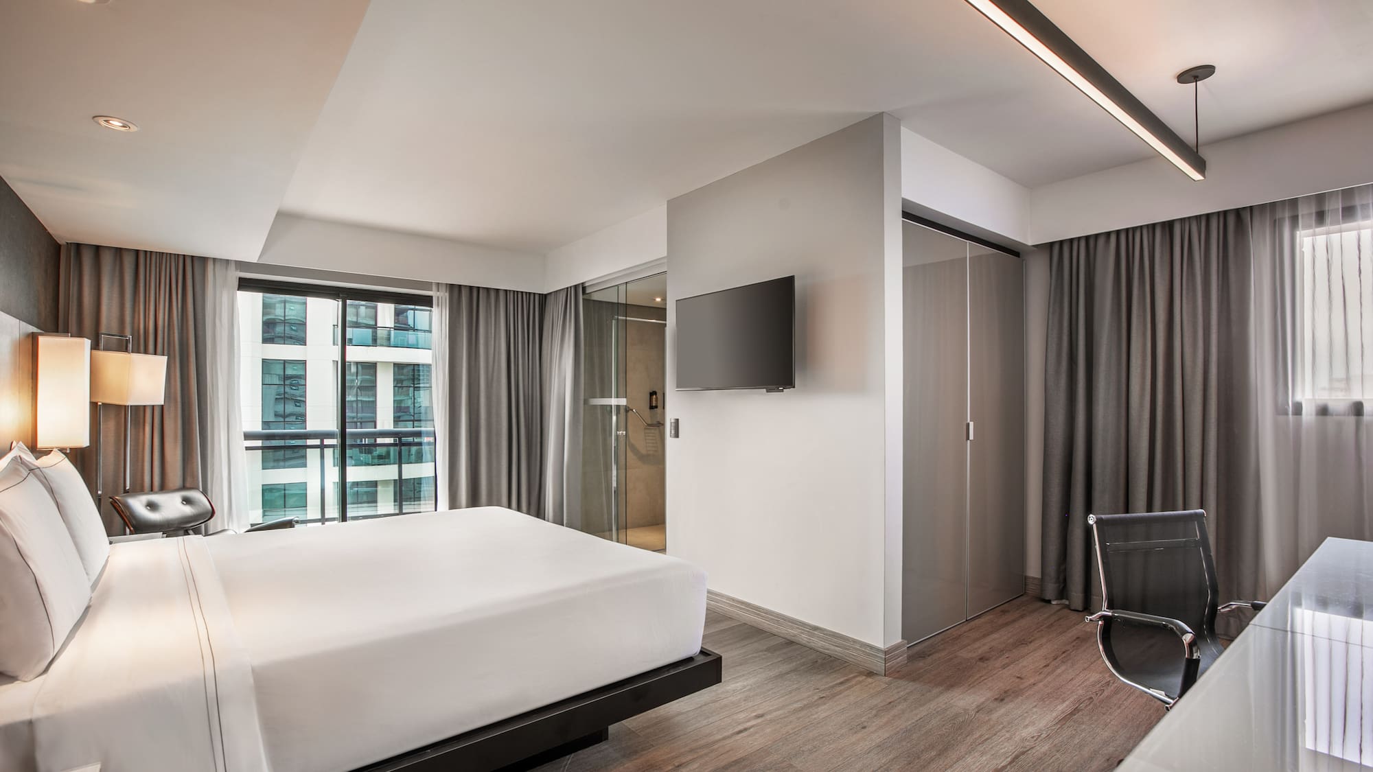 Quarto de hotel moderno com cama de casal, piso de madeira e parede com TV. - Grand Premium com Varanda - Meliá Ibirapuera, São Paulo