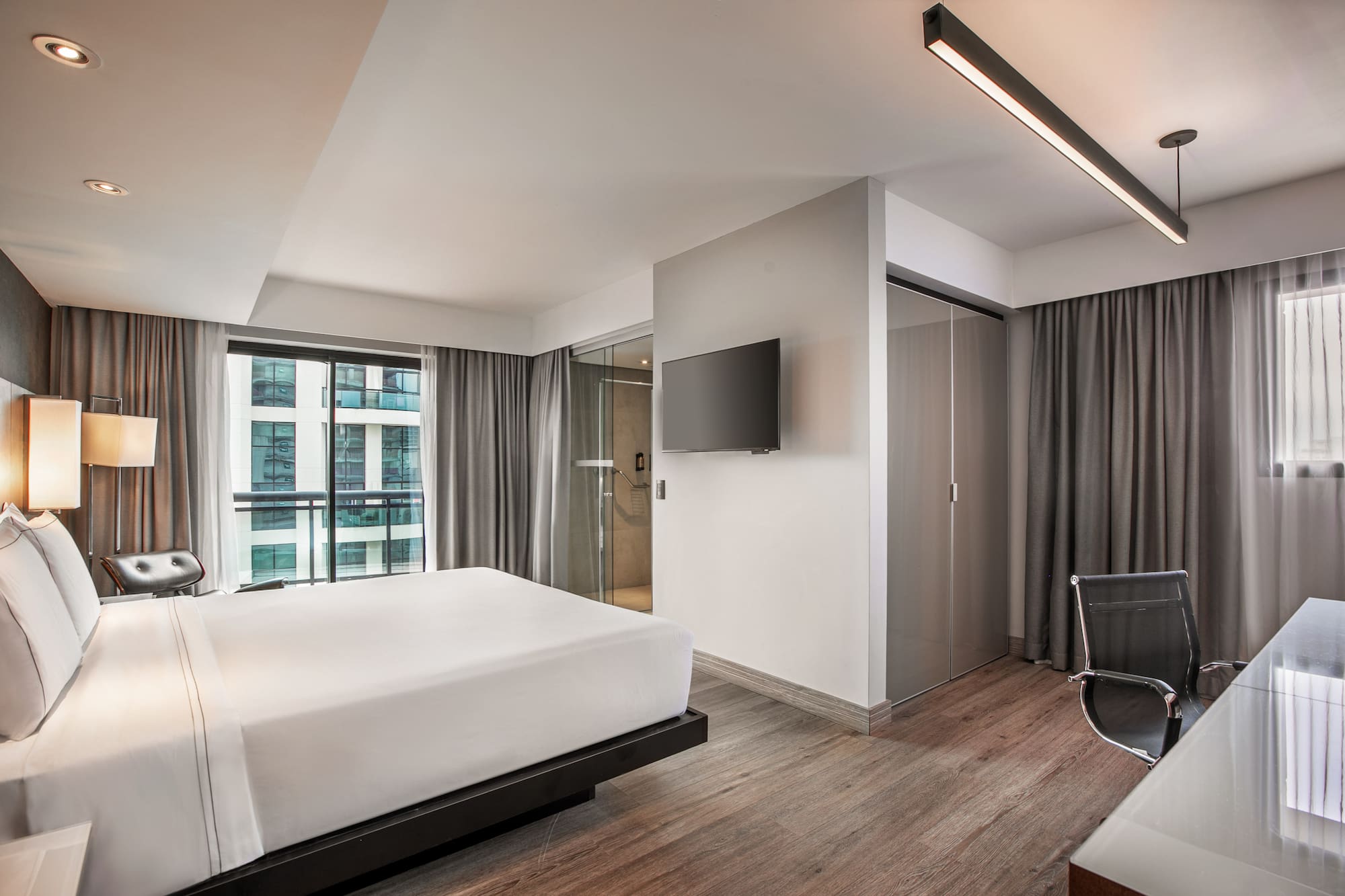 Quarto de hotel moderno com cama de casal, piso de madeira e parede com TV. - Grand Premium com Varanda - Meliá Ibirapuera, São Paulo