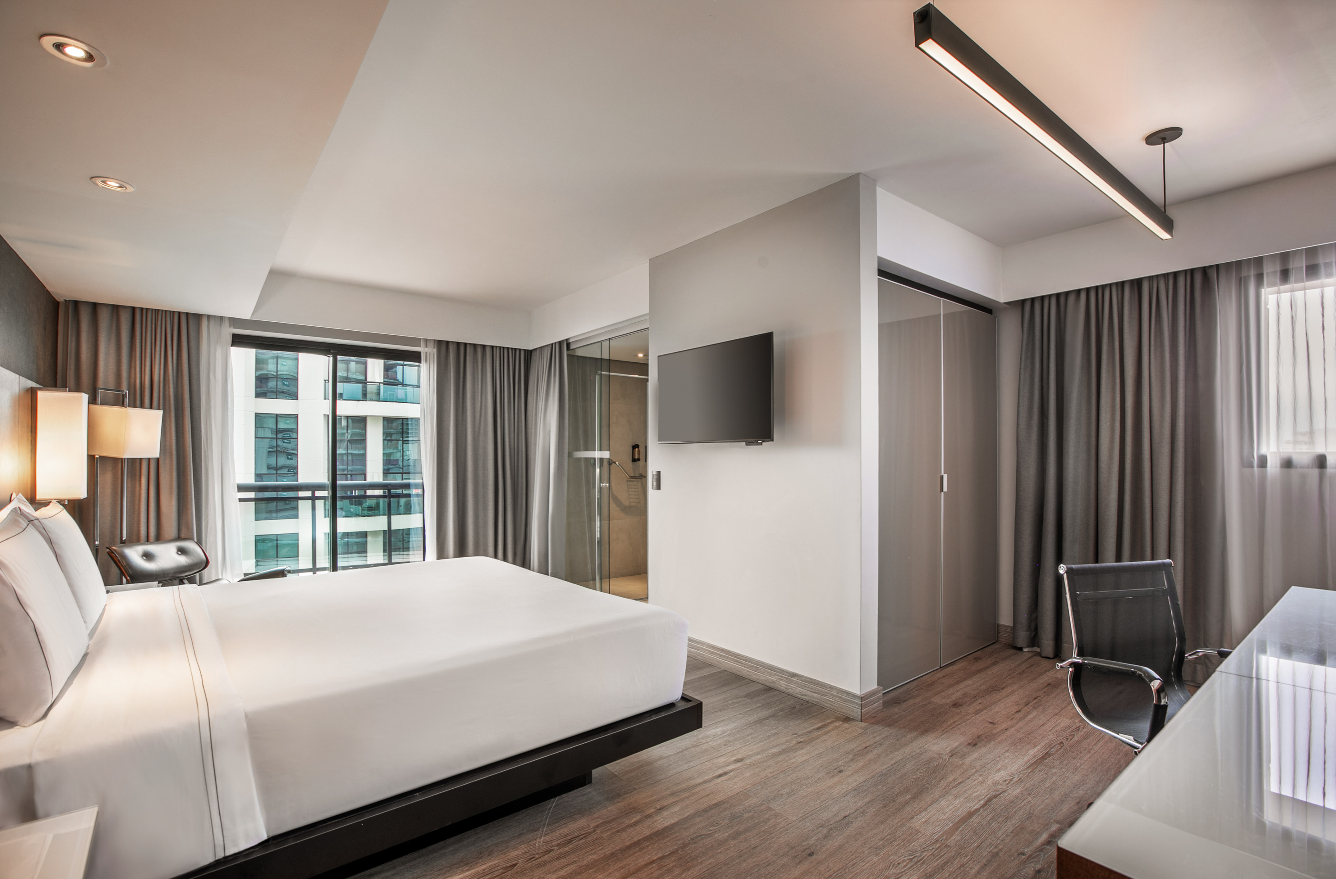 Quarto de hotel moderno com cama de casal, piso de madeira e parede com TV. - Grand Premium com Varanda - Meliá Ibirapuera, São Paulo