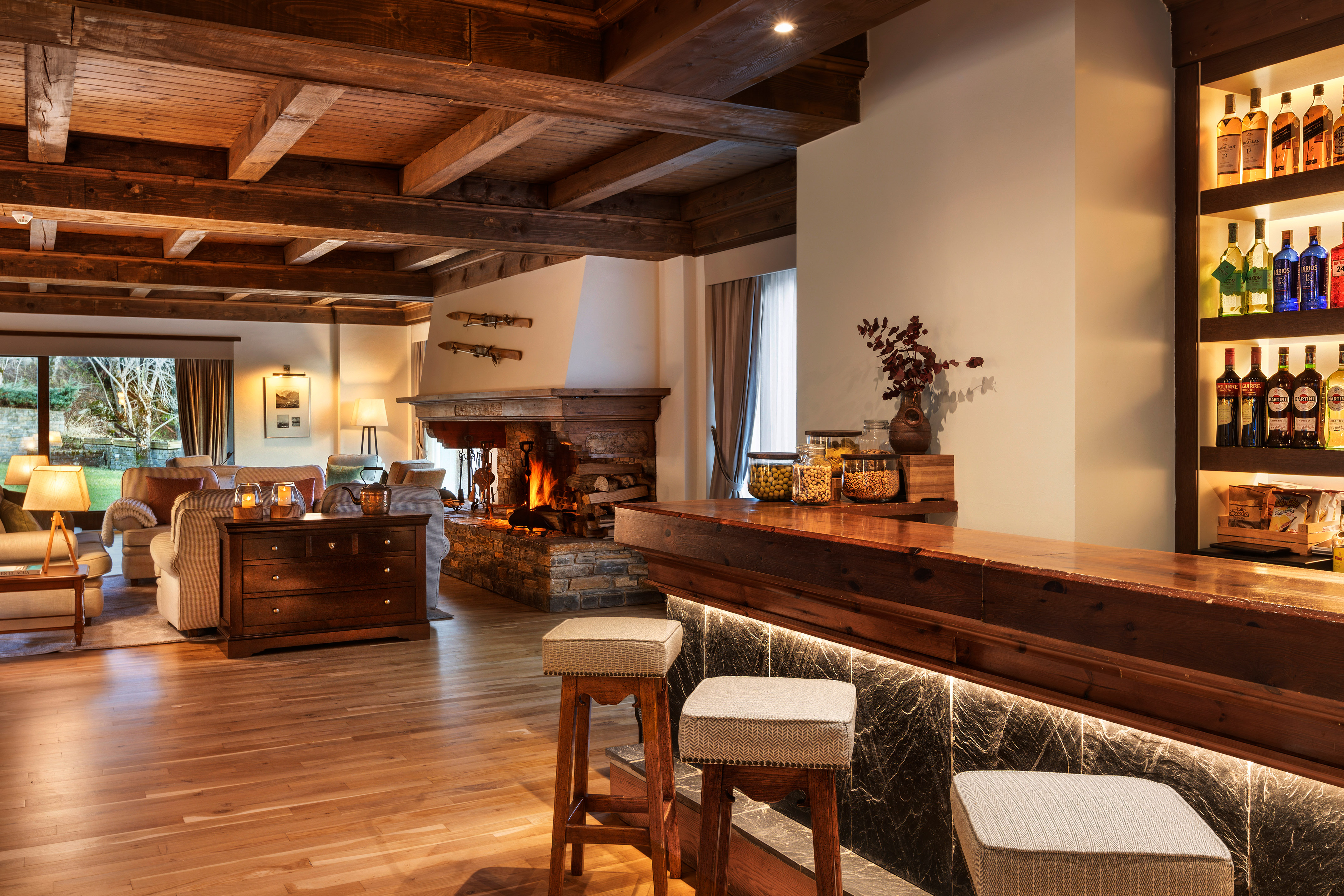 Chalet style lounge with rustic wooden bar, stone fireplace, and exposed beams.