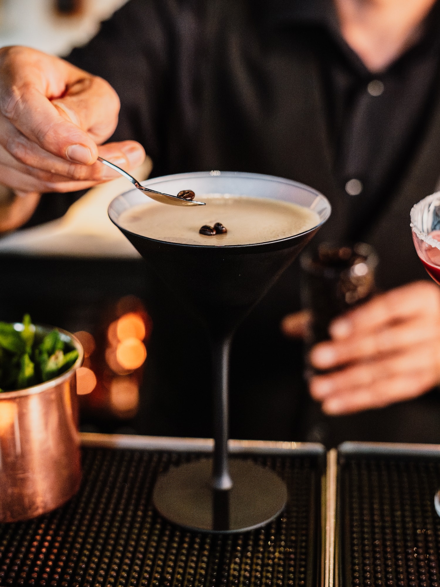 a person pouring a drink into a martini glass