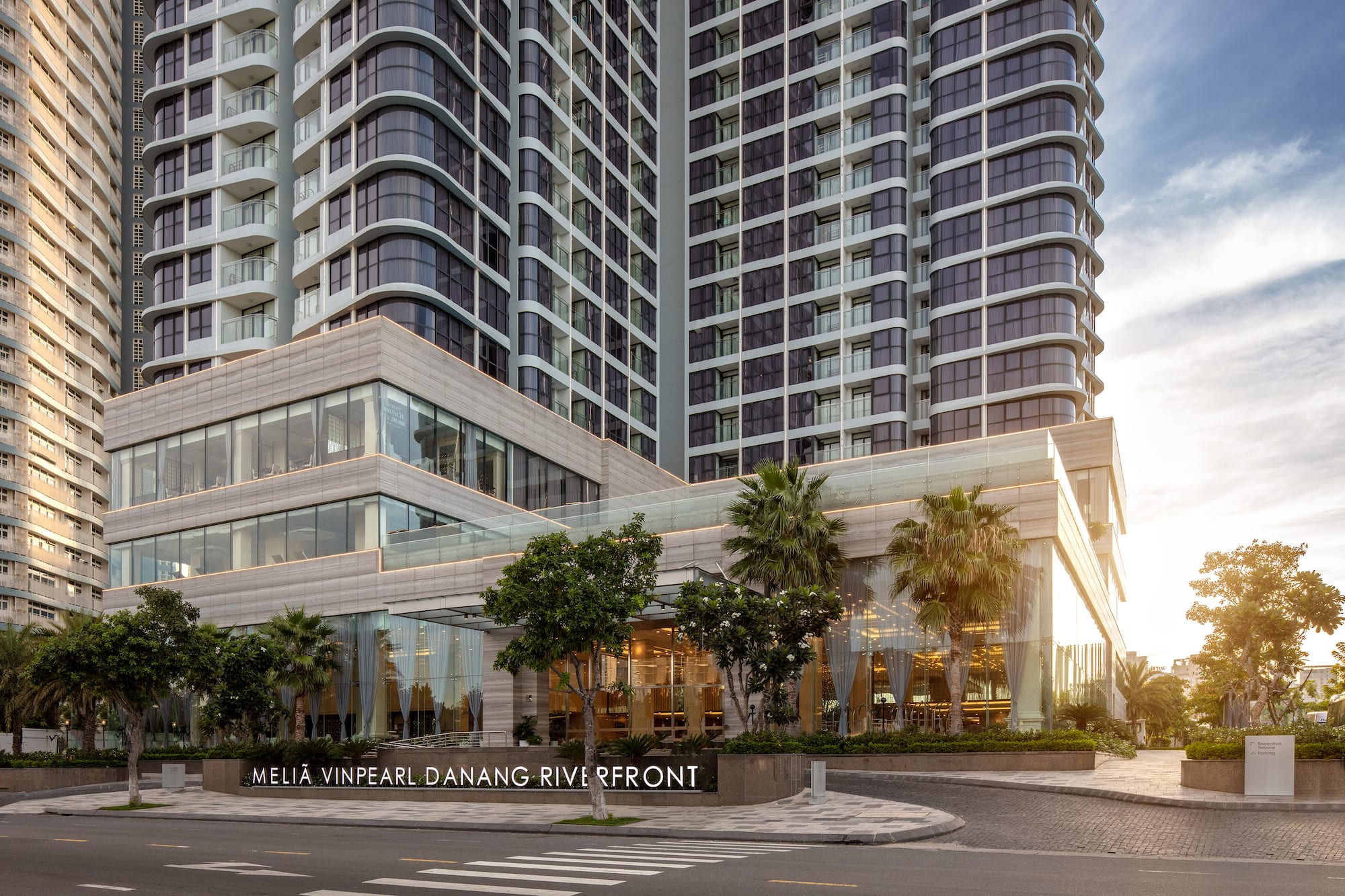 Meliá Vinpearl Danang Riverfront modern hotel with glass facade and palm trees.