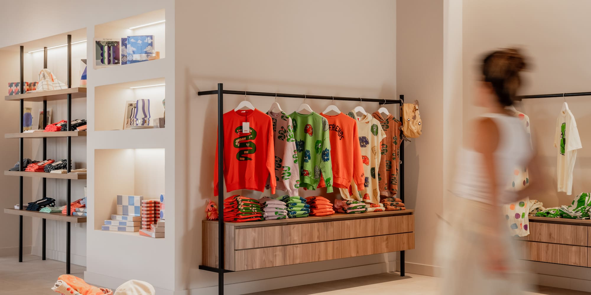 Vibrant clothing display in a modern boutique with sweaters on rack and shelving.
