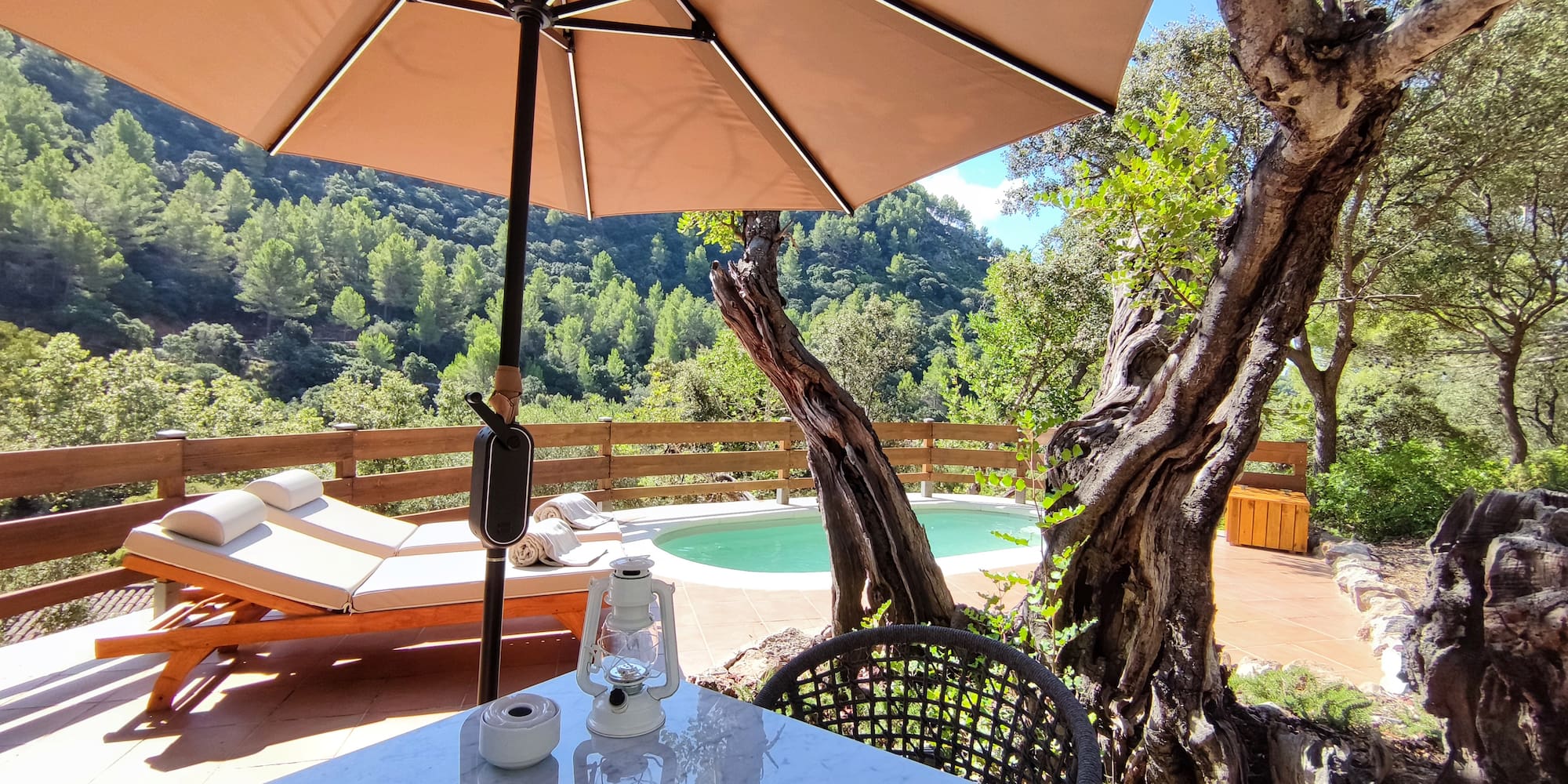 a table and chair with an umbrella and a pool in the background
