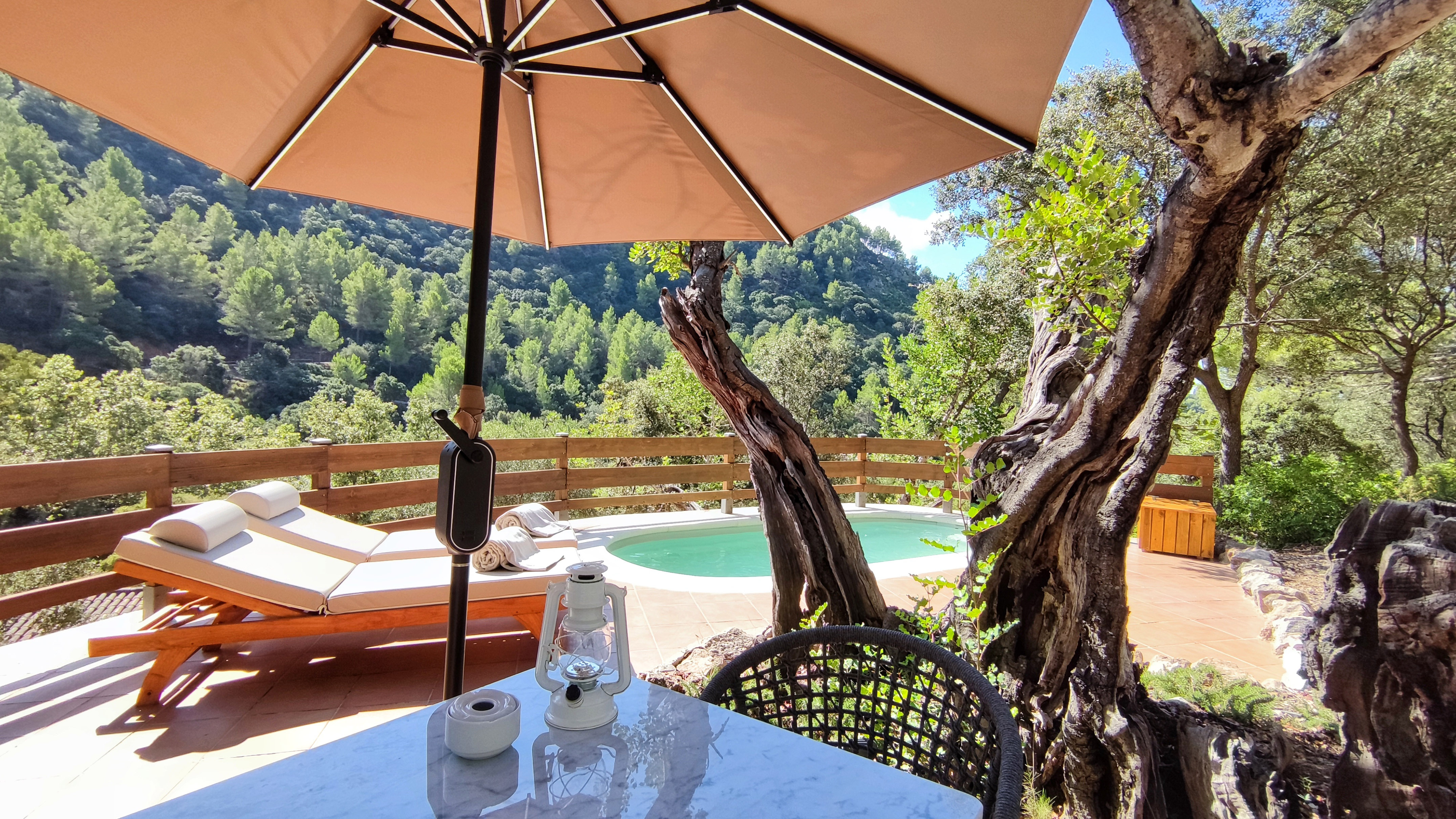 a table and chair with an umbrella and a pool in the background