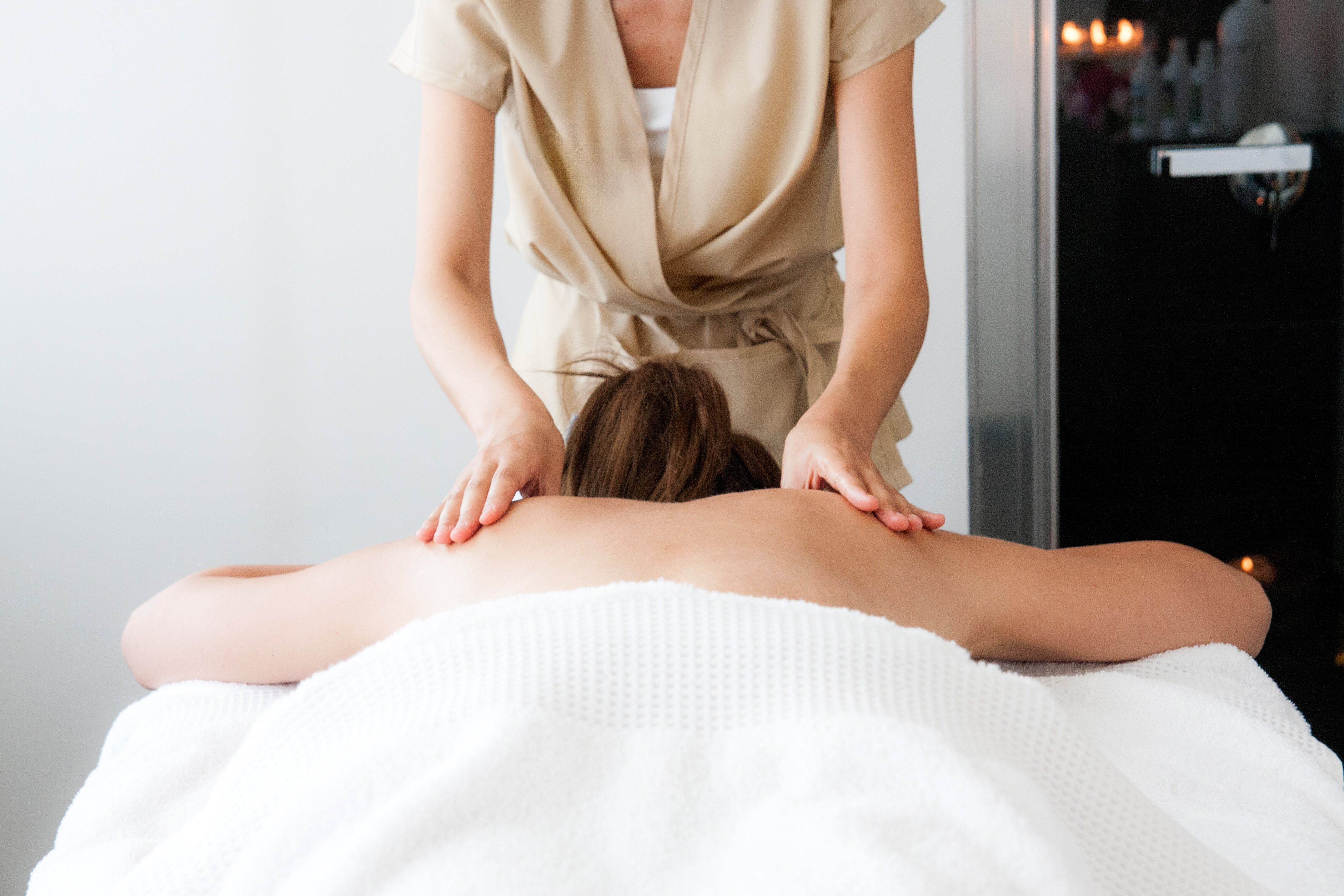 Woman receiving a back massage from a therapist in a spa setting.