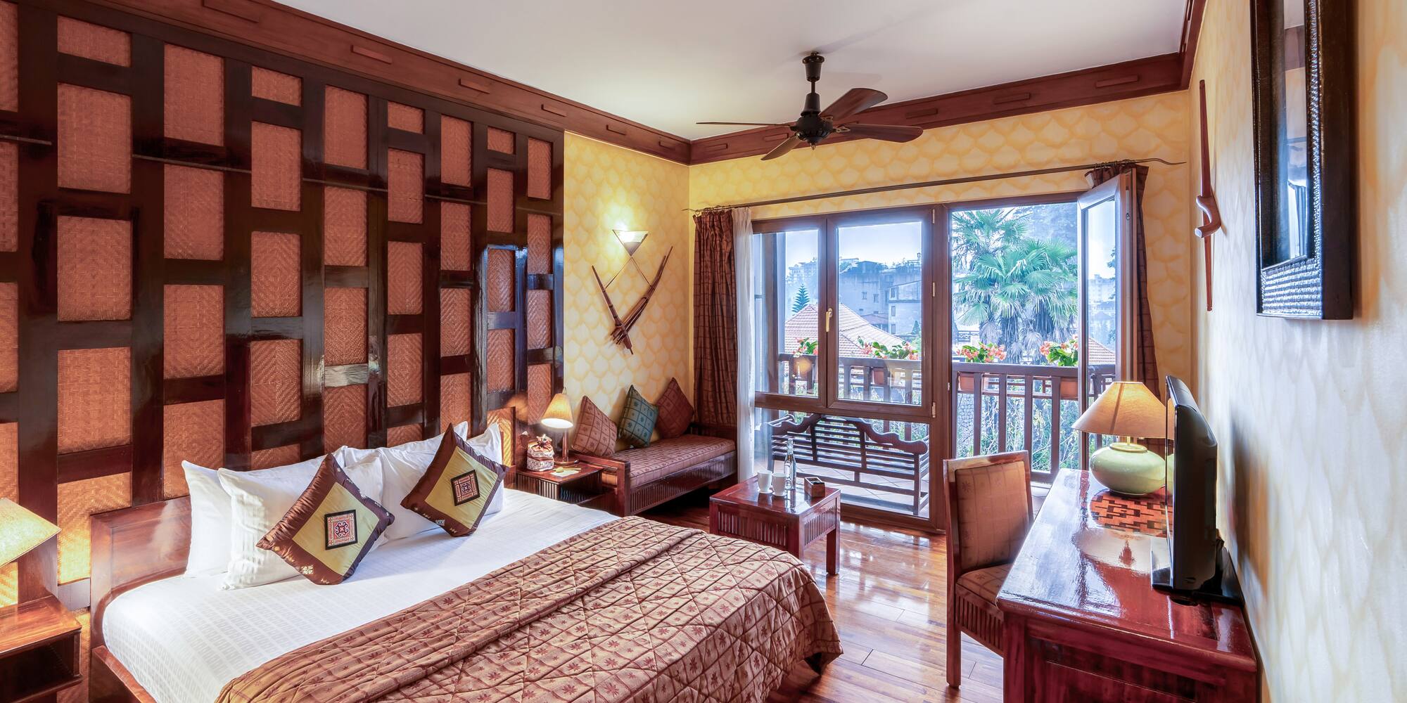 a room with a bed and a desk and a fan