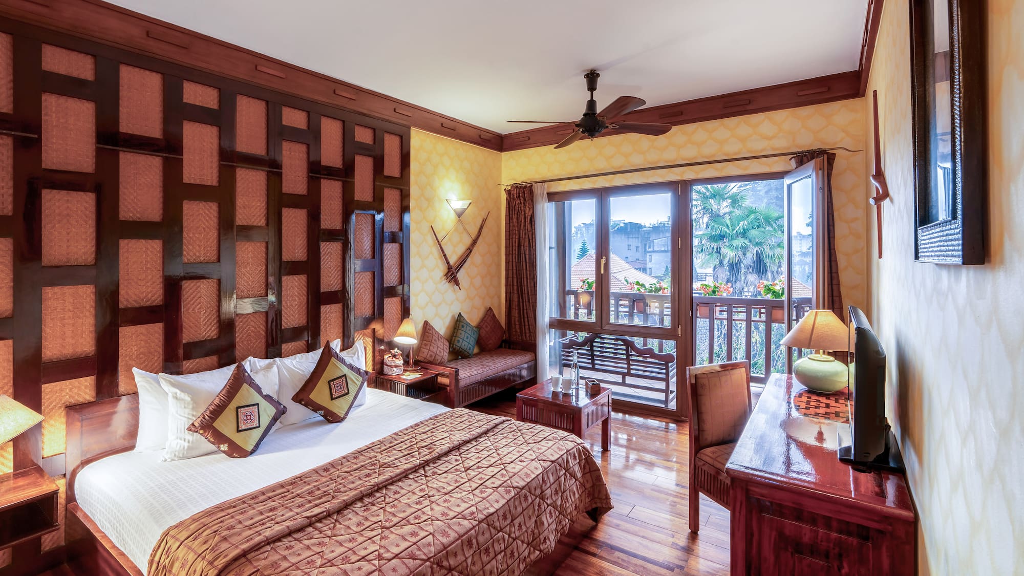 a room with a bed and a desk and a fan