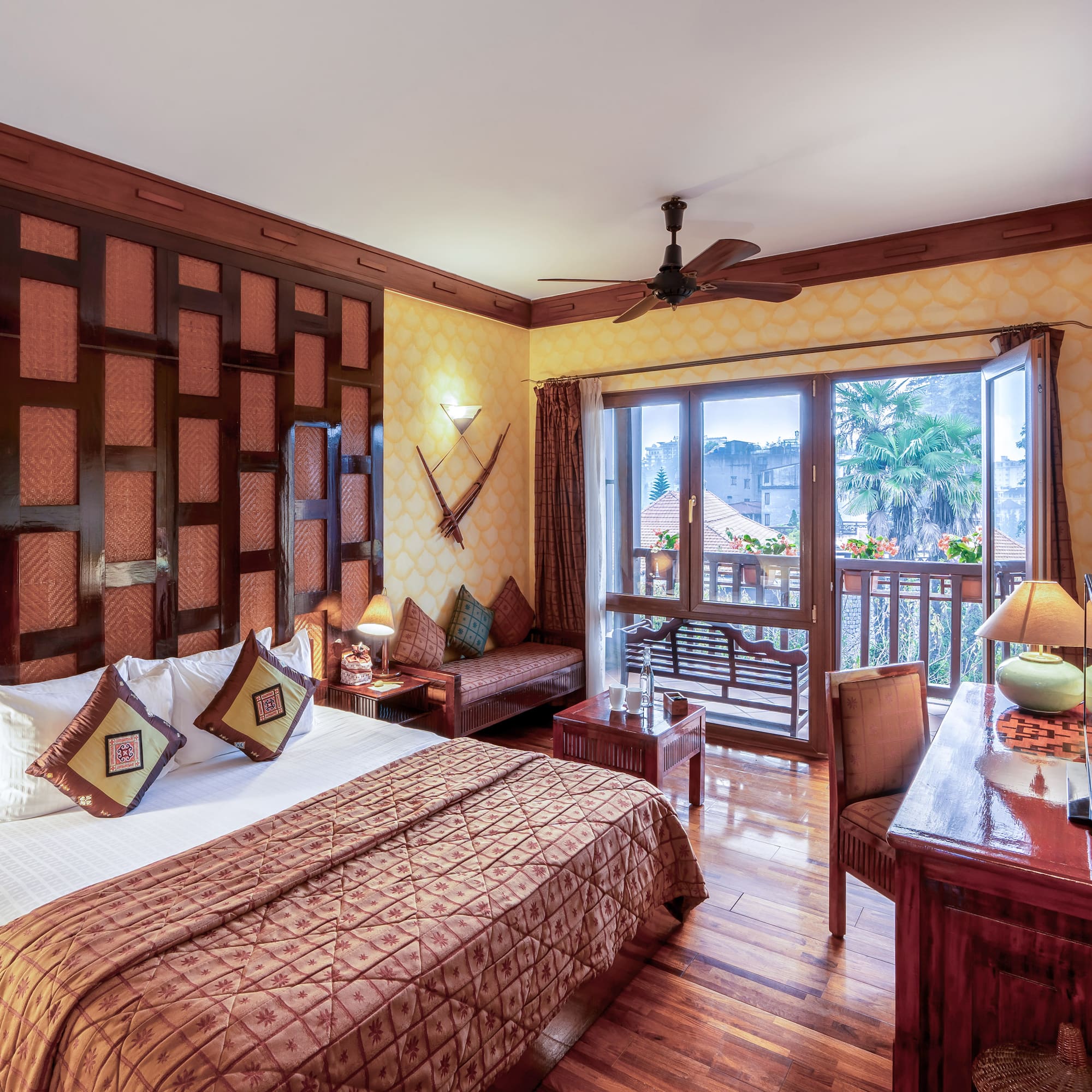 a room with a bed and a desk and a fan