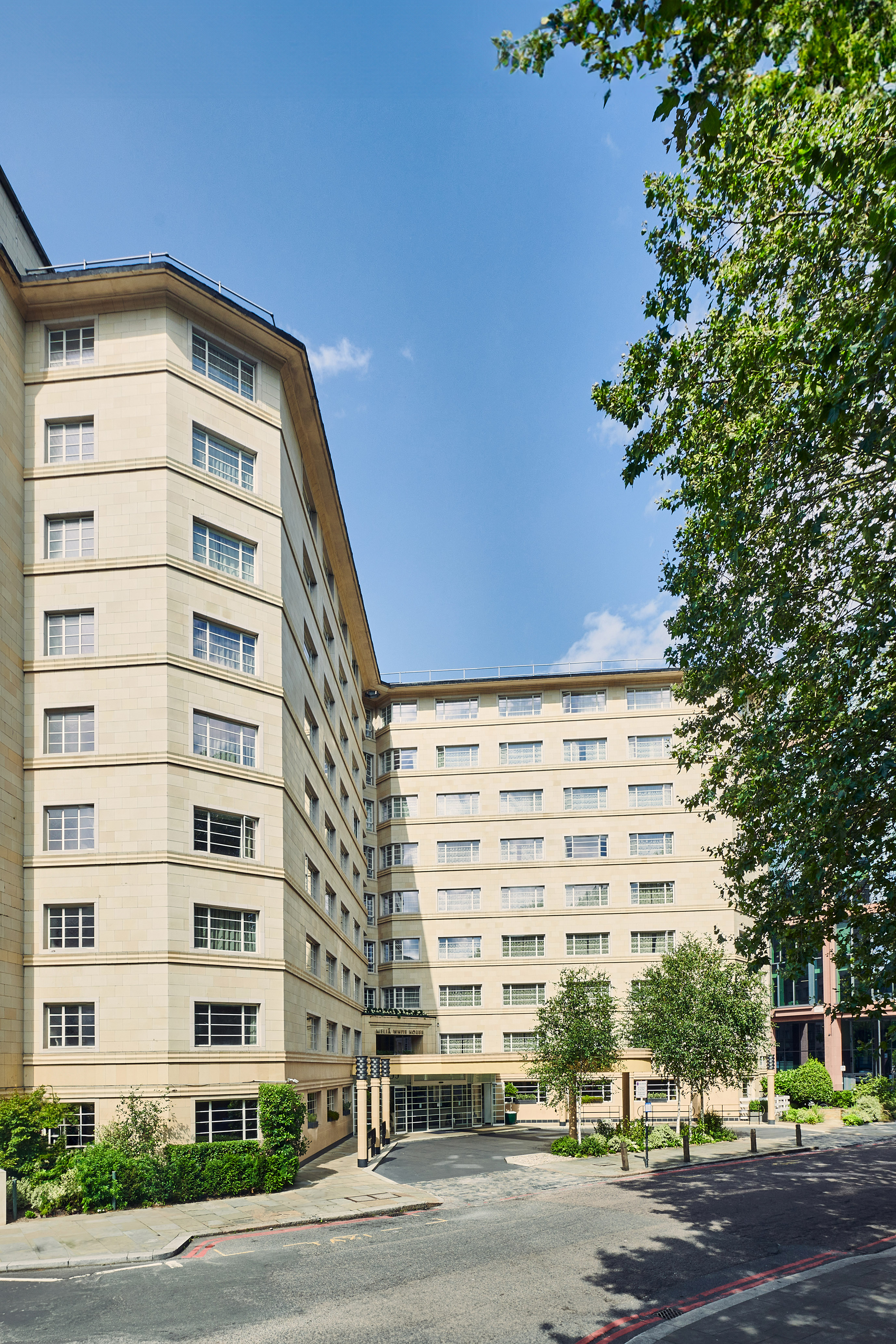 Melia White House hotel, multi-story cream building, street, trees, blue sky.