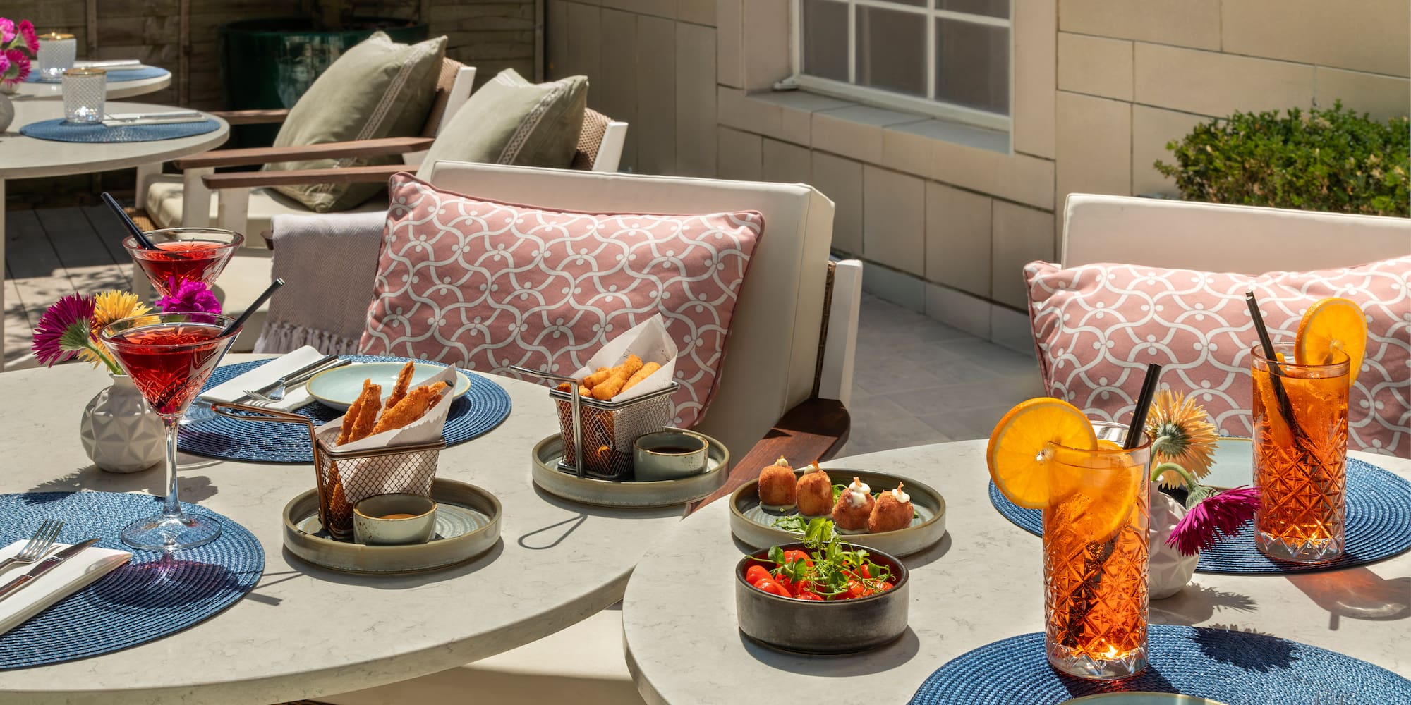Outdoor patio dining with cocktails, various appetizers, and fresh salad.