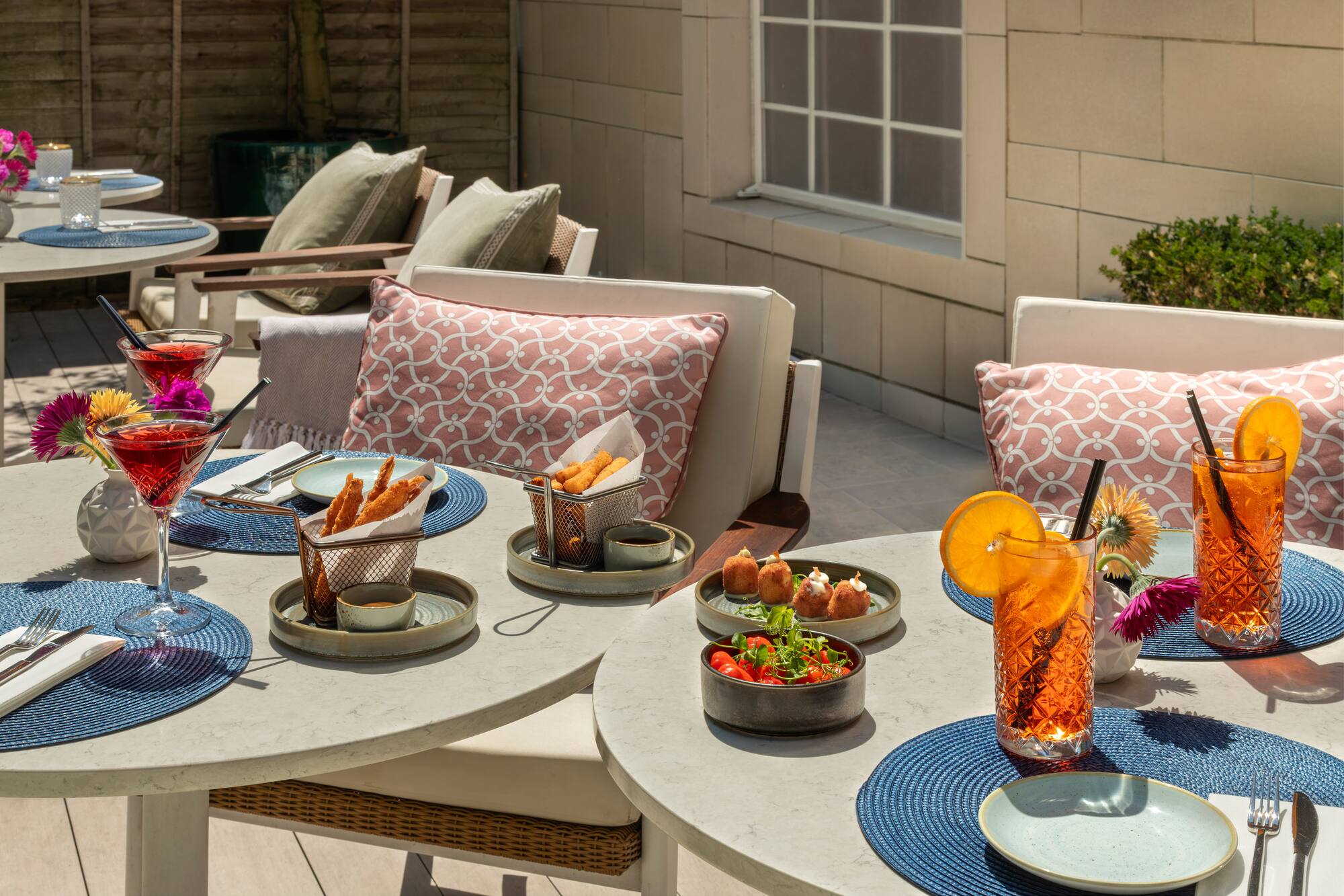 Outdoor patio dining with cocktails, various appetizers, and fresh salad.