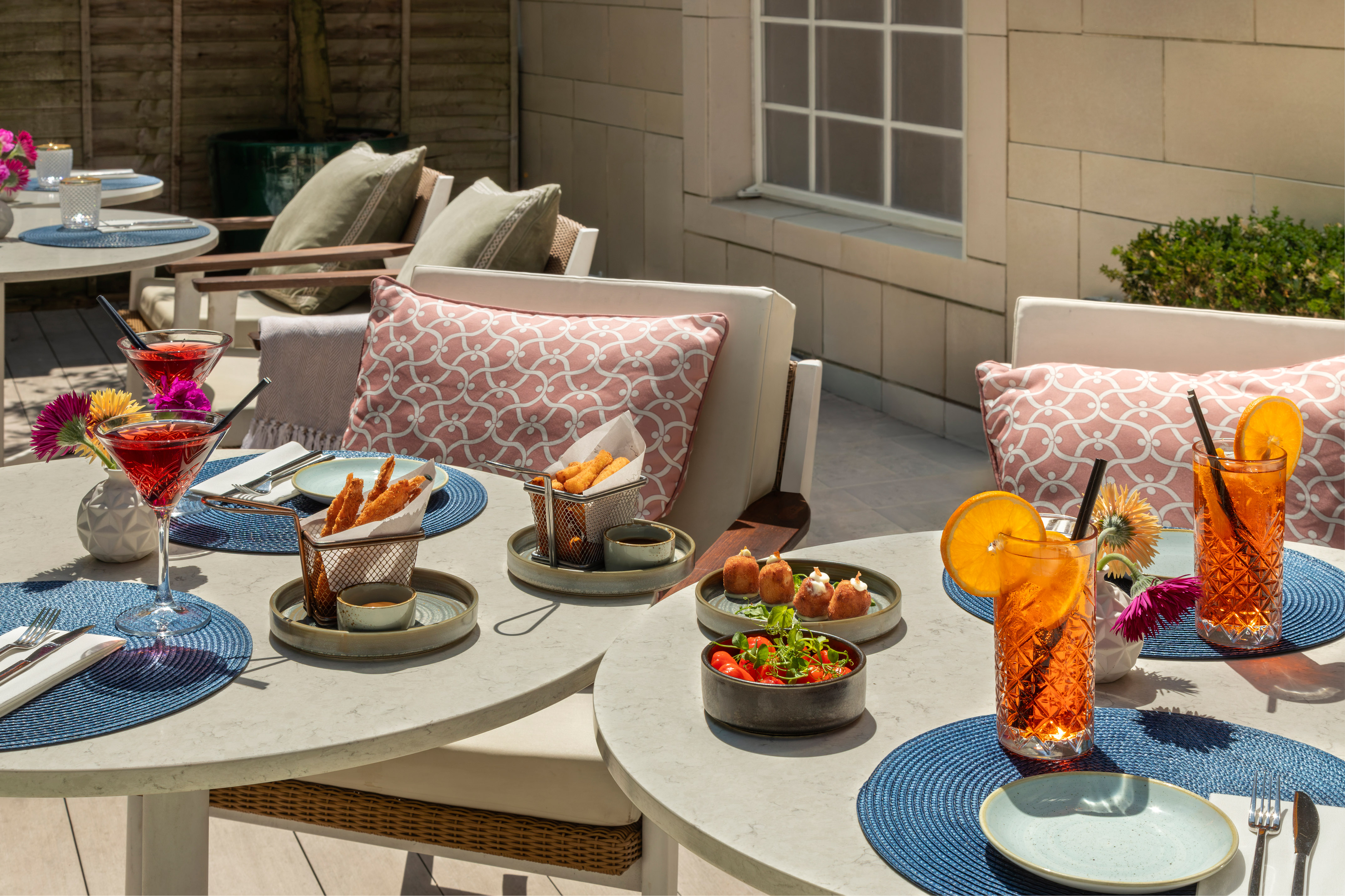 Outdoor patio dining with cocktails, various appetizers, and fresh salad.