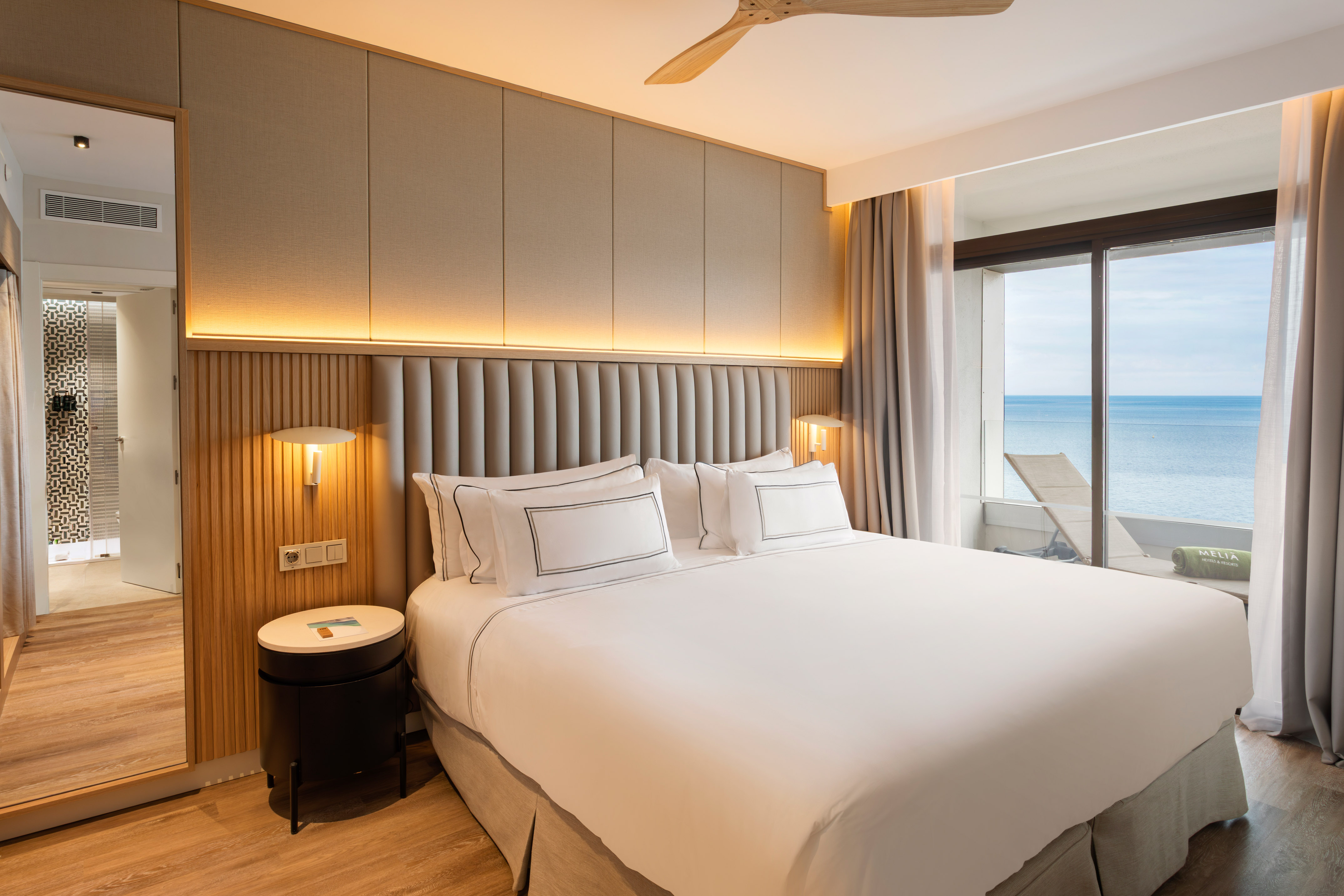Modern hotel room with ocean view, king bed, and balcony.