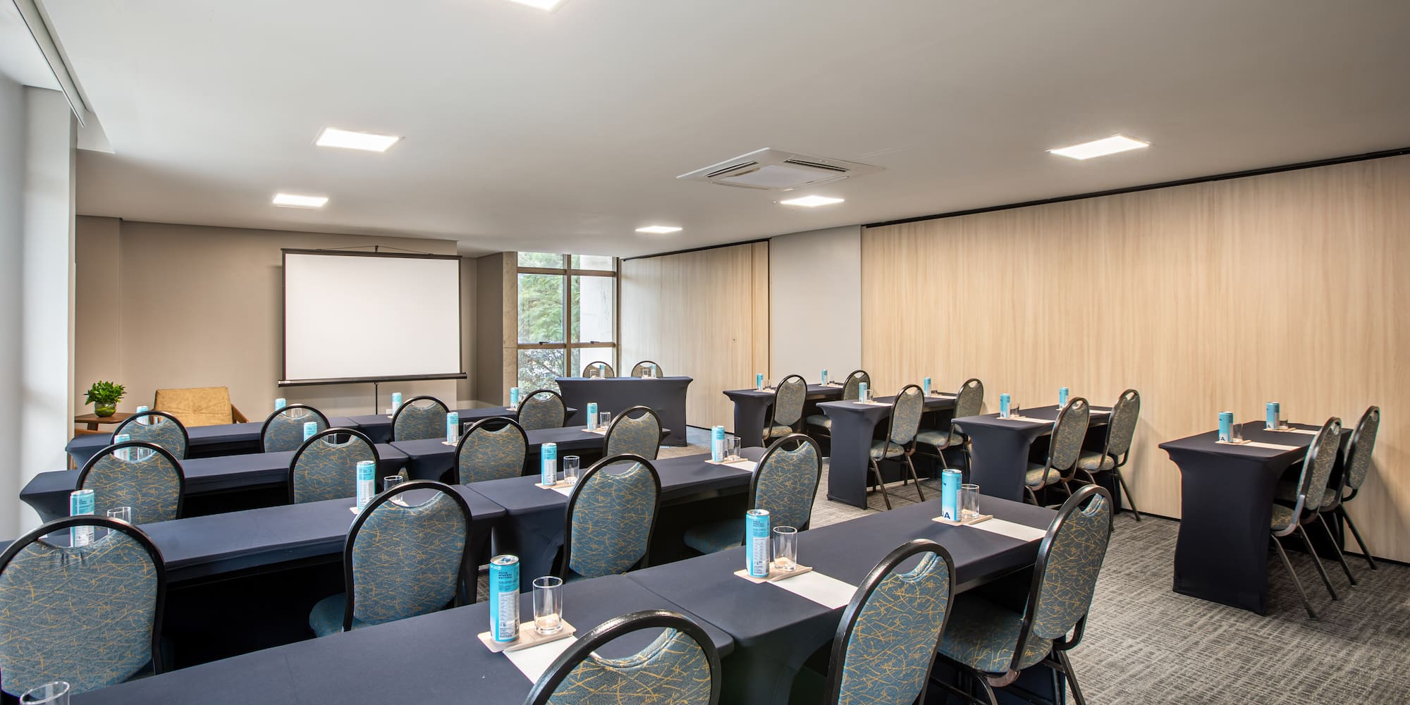 Modern conference room with navy tables, chairs, and large projection screen.