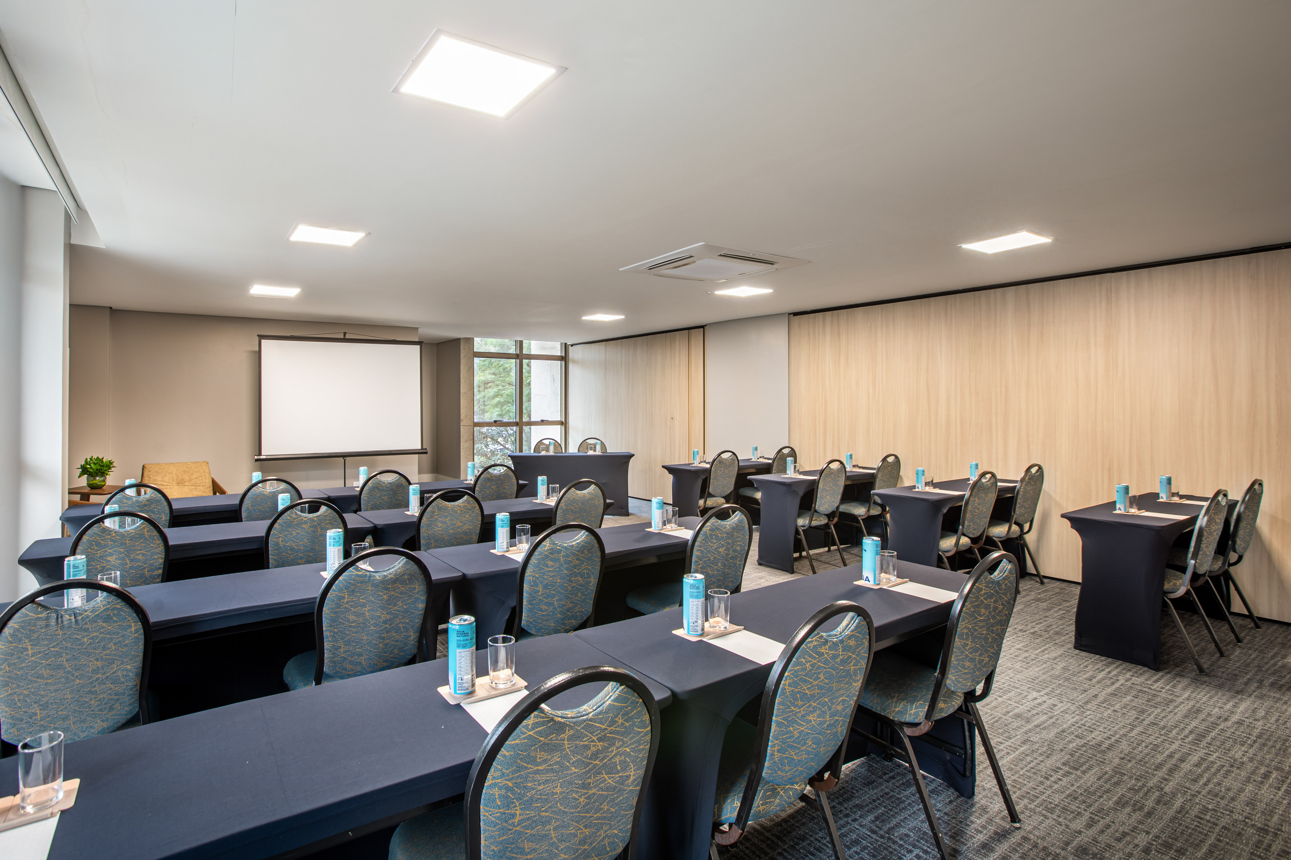 Modern conference room with navy tables, chairs, and large projection screen.