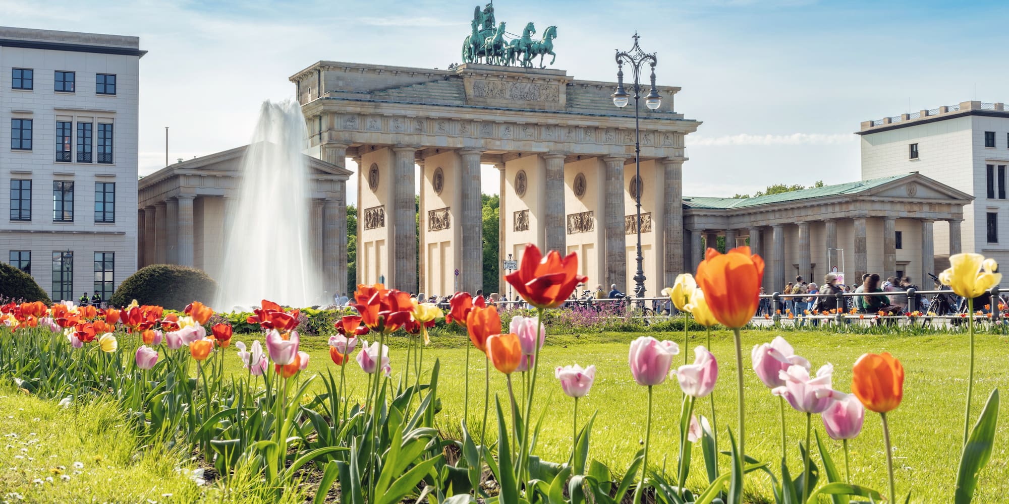 a large building with a fountain and flowers