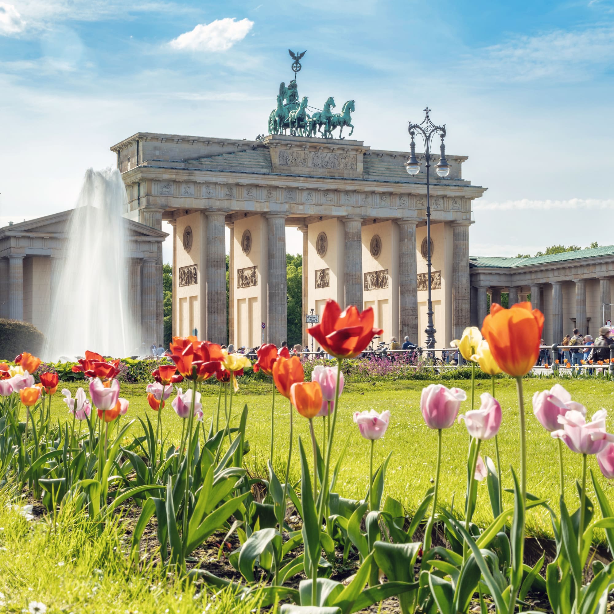 a large building with a fountain and flowers