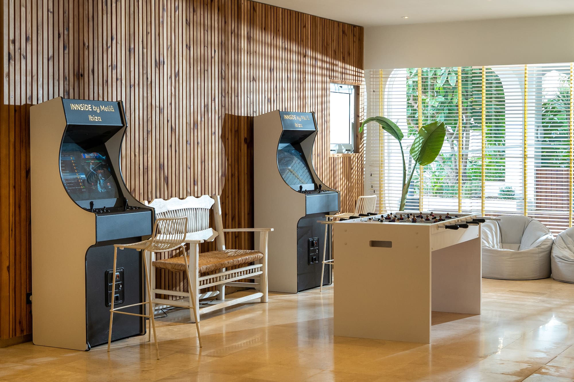 Stylish hotel game room featuring arcade machines, foosball, and wooden walls.