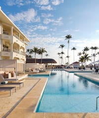 a swimming pool with lounge chairs and palm trees