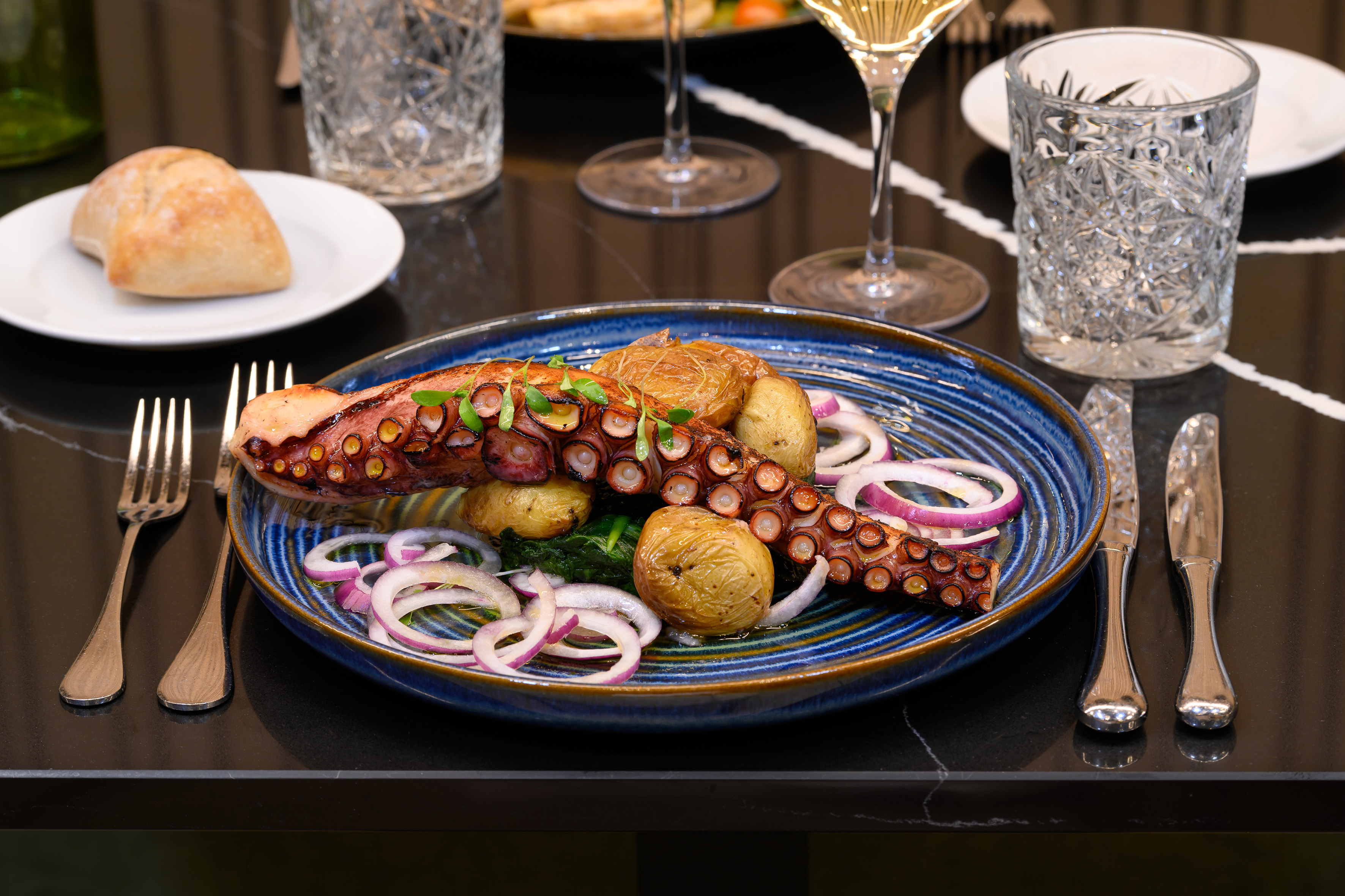 Grilled octopus tentacles with roasted potatoes and red onion rings.