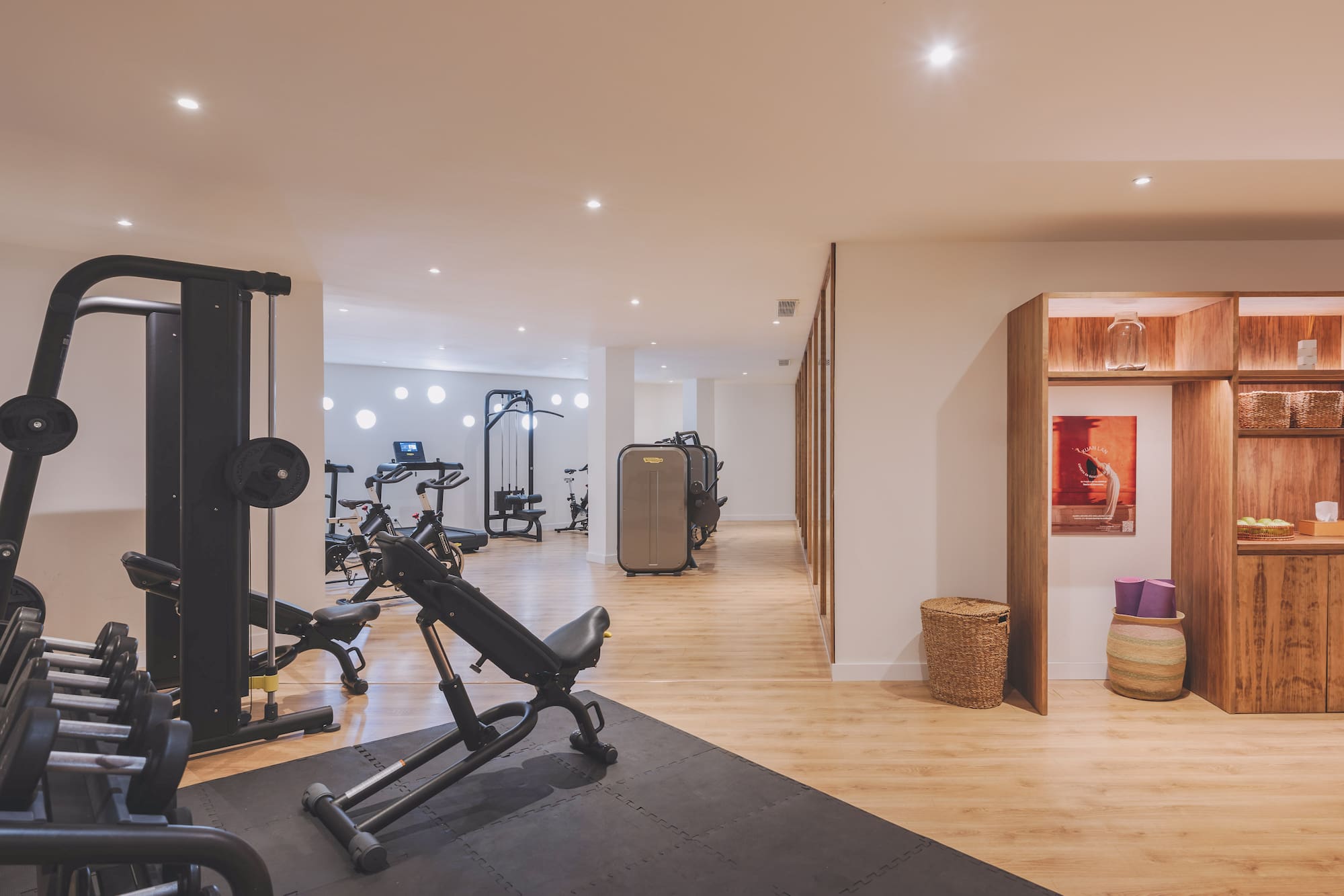 Modern gym with strength training equipment, dumbbells, and yoga mats.