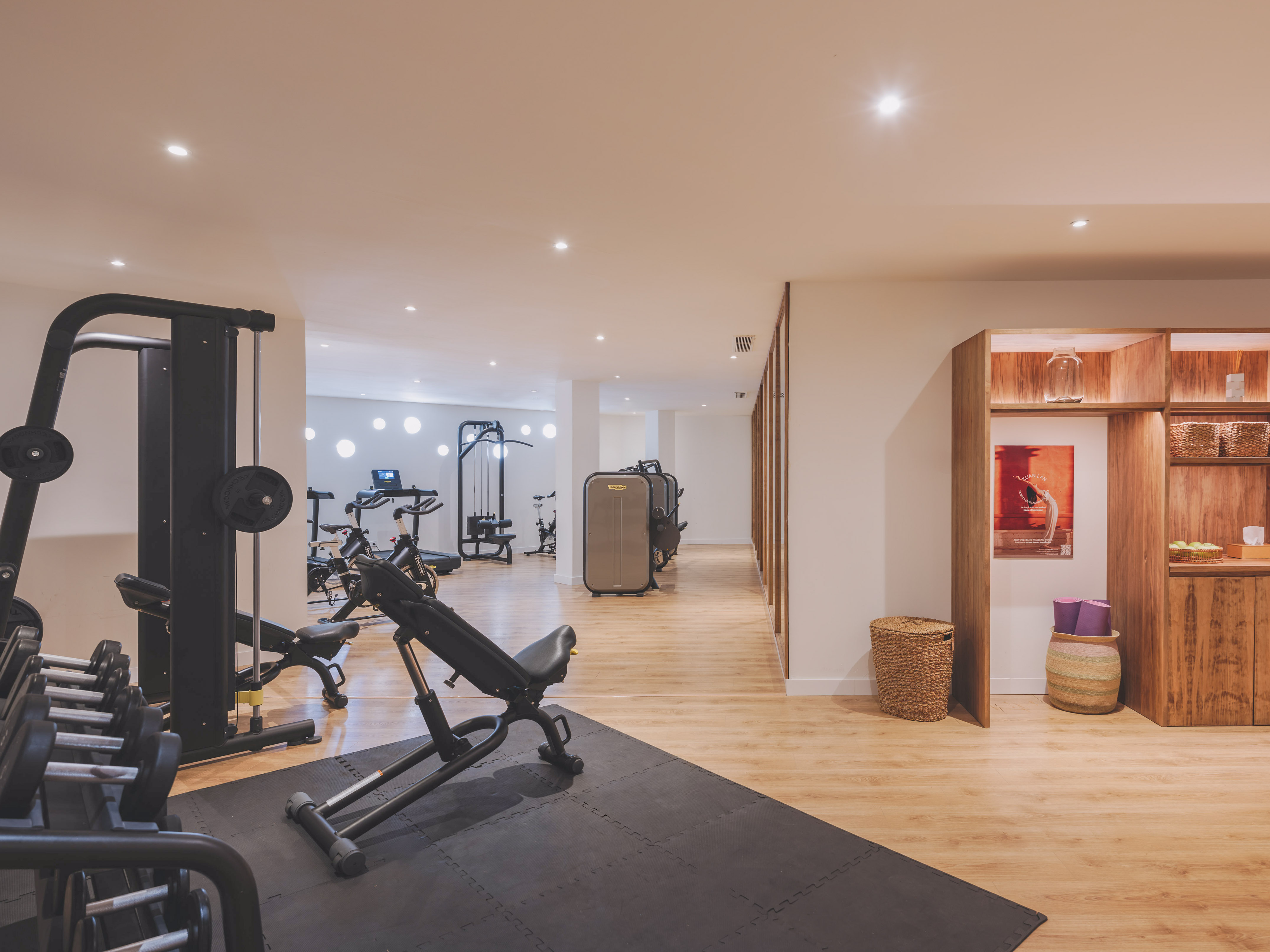 Modern gym with strength training equipment, dumbbells, and yoga mats.