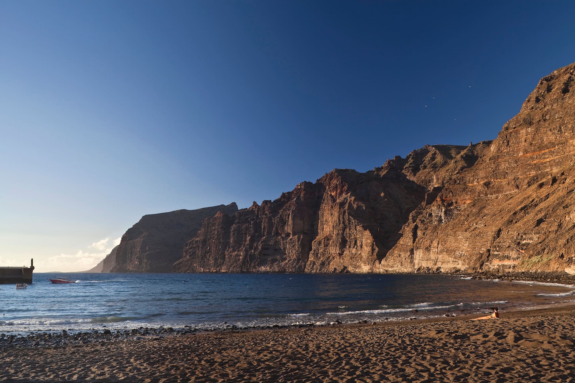 a beach with a body of water and a rocky cliff