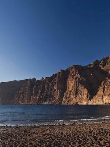 a beach with a body of water and a rocky cliff