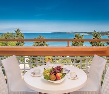a table with fruit on it and chairs on a balcony overlooking the ocean