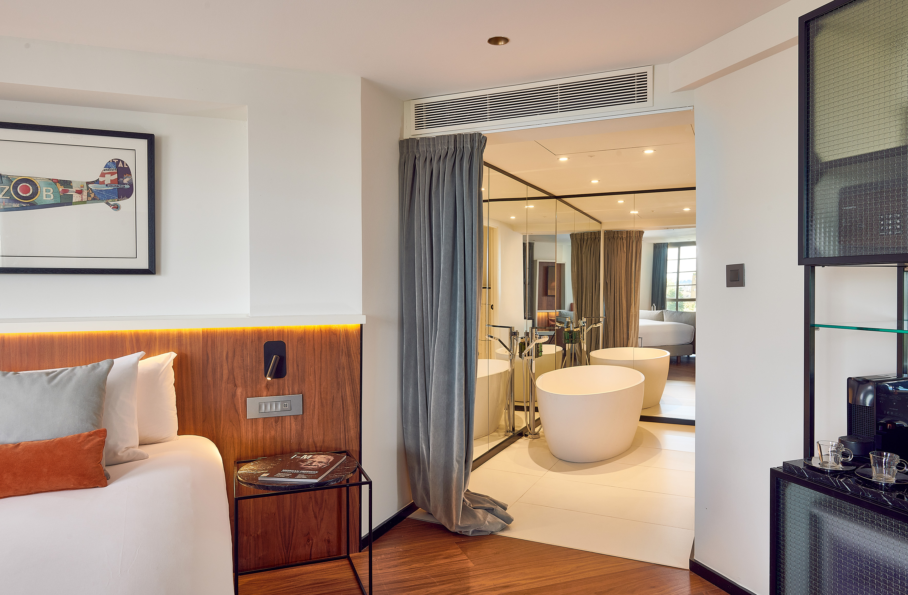 Modern hotel room suite with open bathroom, two freestanding tubs.