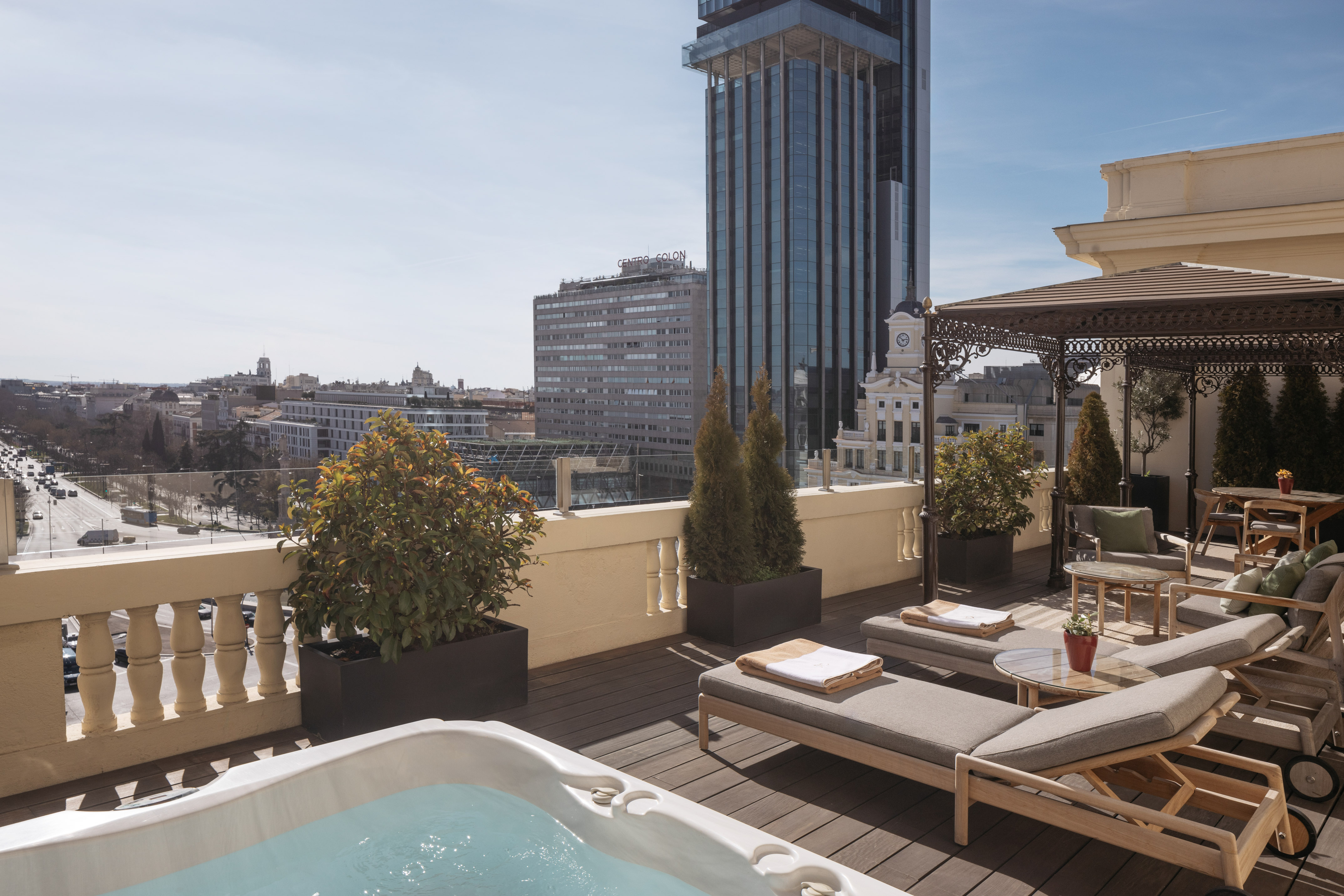 Rooftop terrace with hot tub, loungers, and Madrid city skyline.