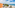 a beach with a building and trees and a body of water