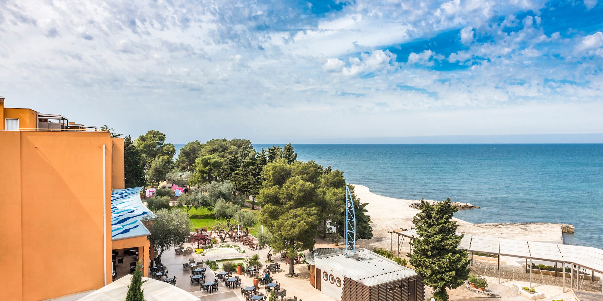 a beach with a building and trees and a body of water