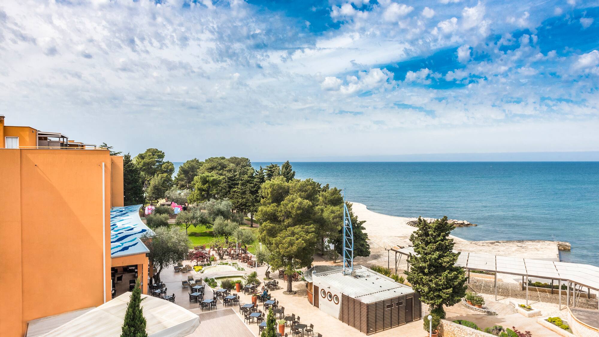 a beach with a building and trees and a body of water