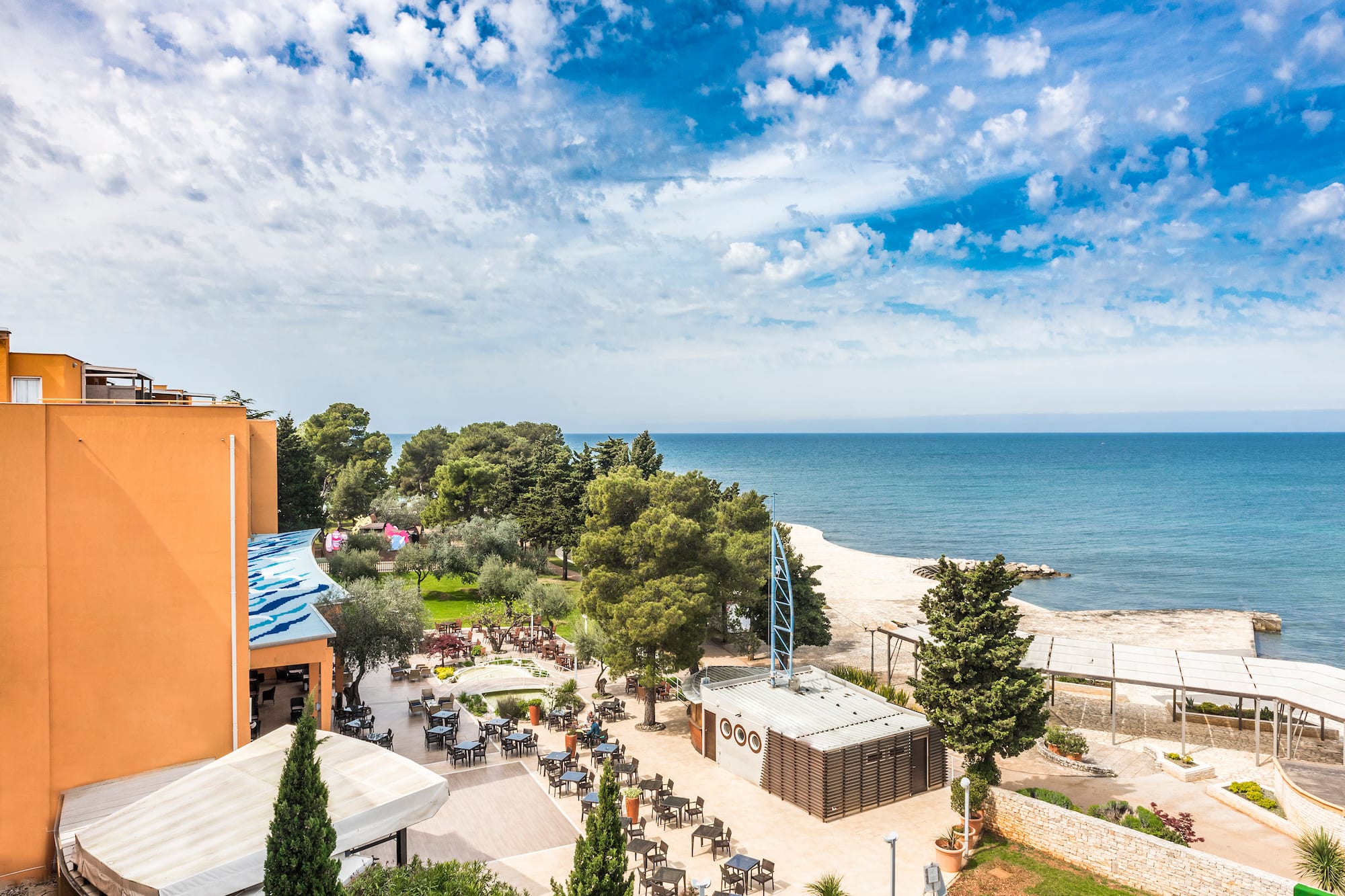 a beach with a building and trees and a body of water