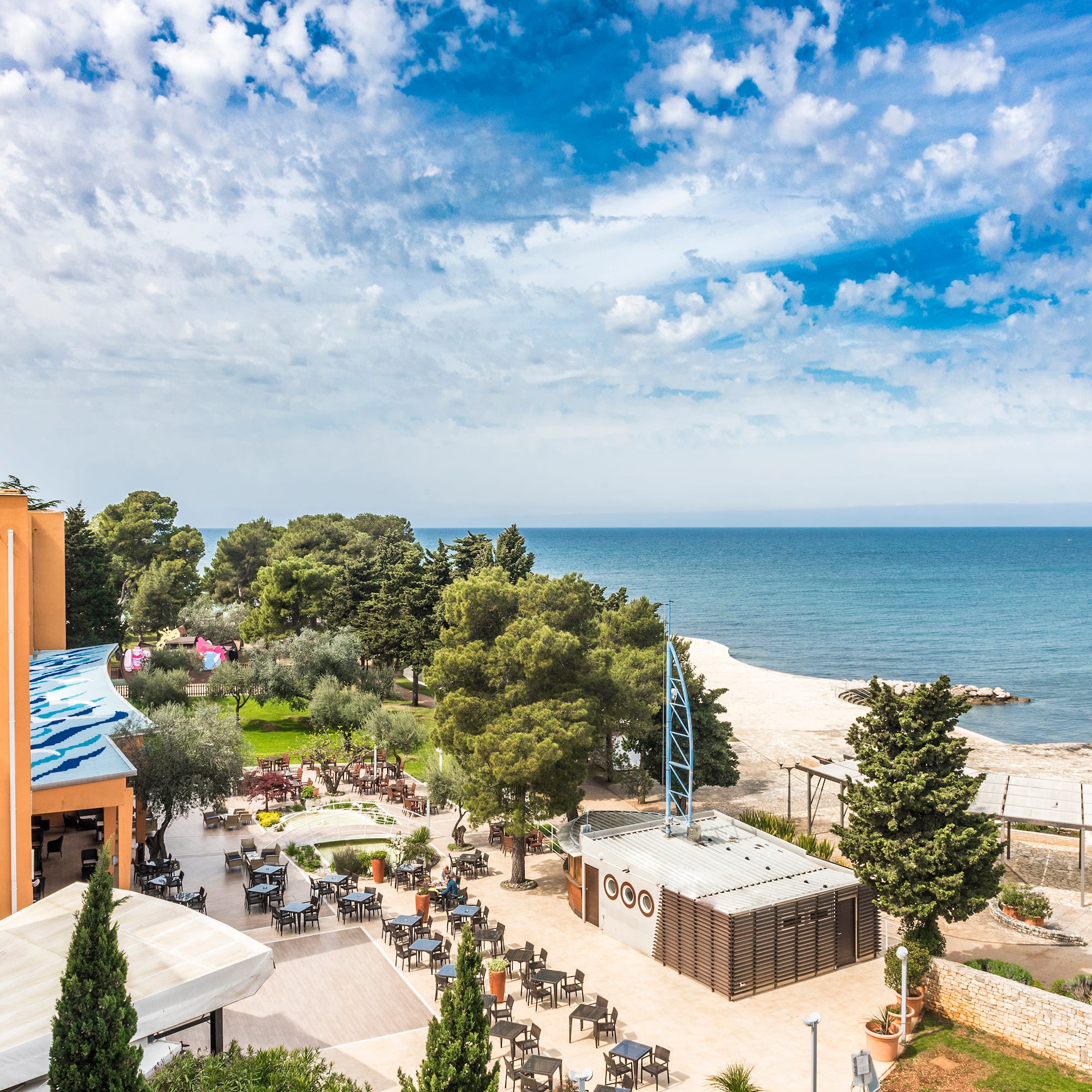 a beach with a building and trees and a body of water