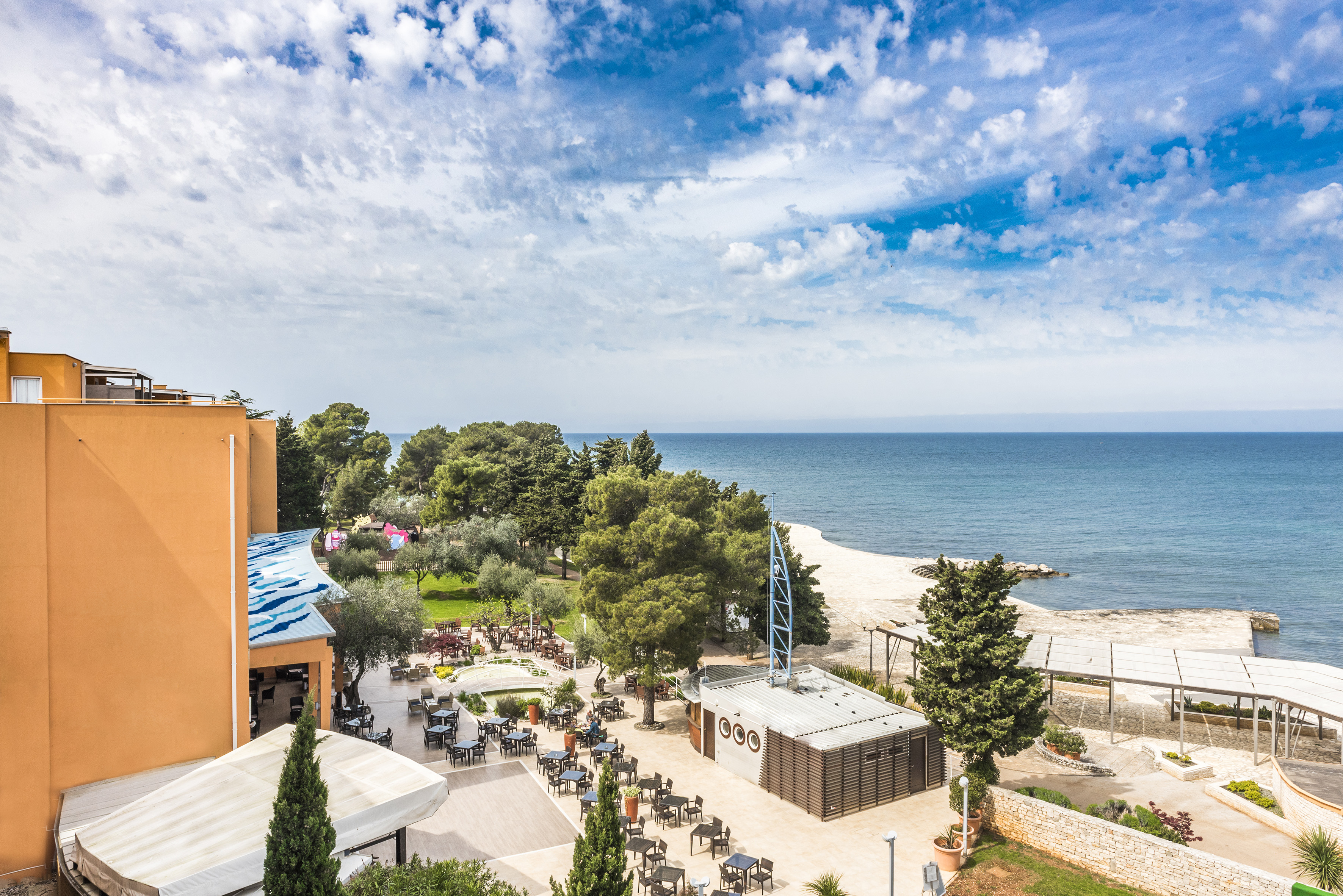 a beach with a building and trees and a body of water