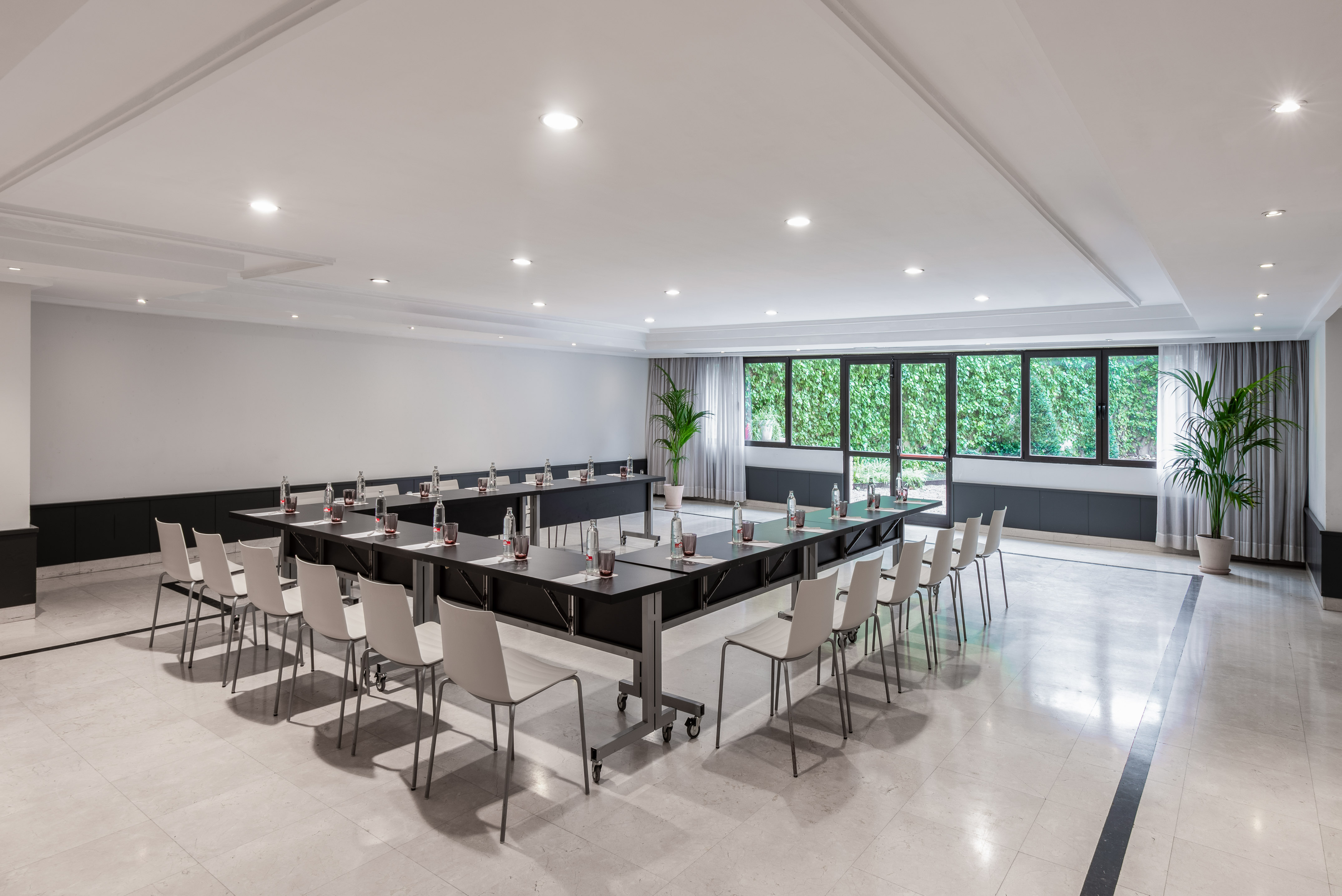 U-shape conference room with tables, chairs, and bright windows.