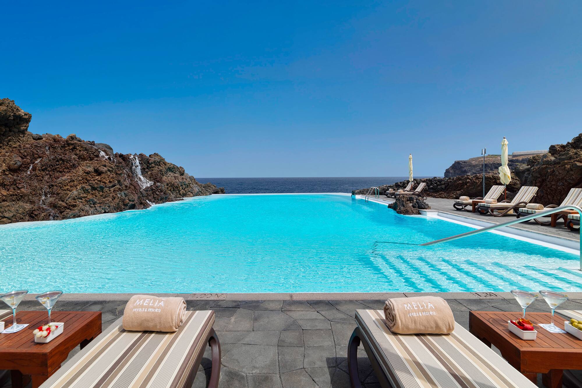 Luxury Meliá resort infinity pool with ocean view and sun loungers.