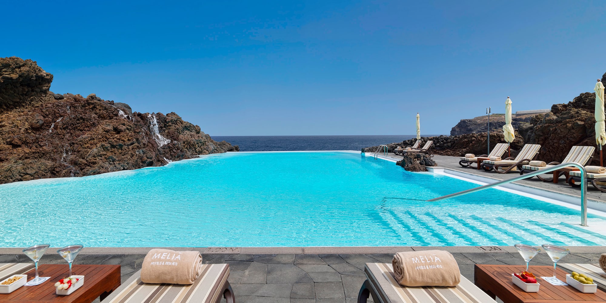 a pool with chairs and rocks in the background