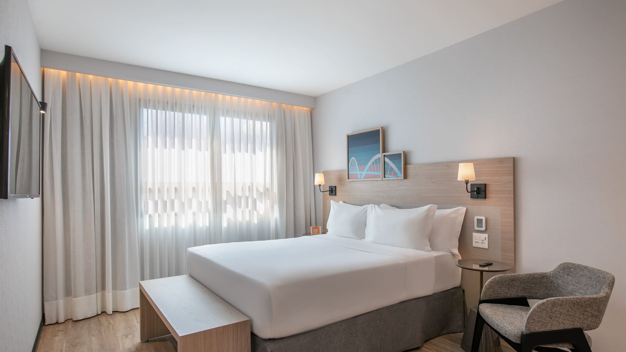 Bright modern hotel room with queen bed, wood headboard, and large window.