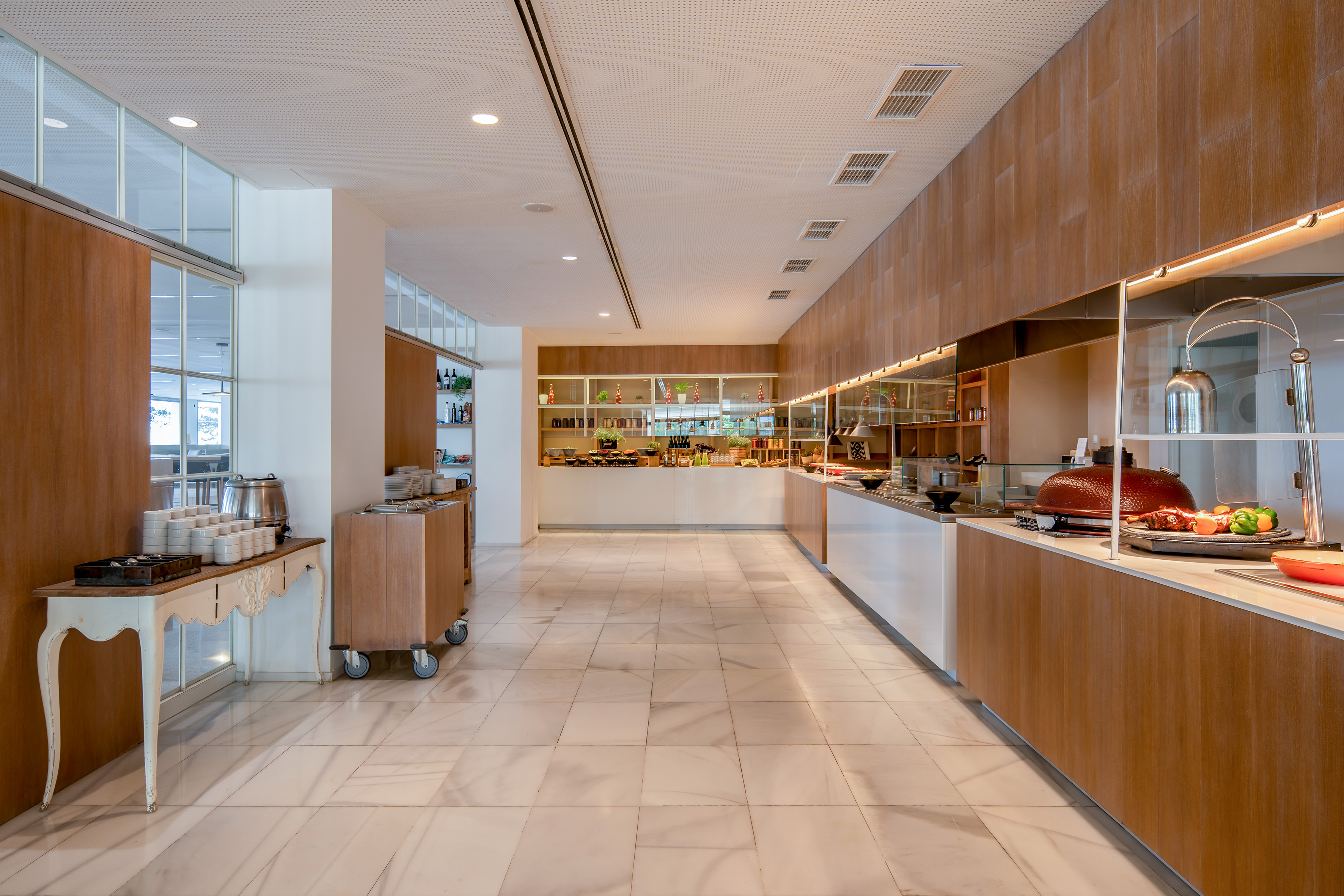 Modern hotel buffet with food stations, warm wood, and marble floors.
