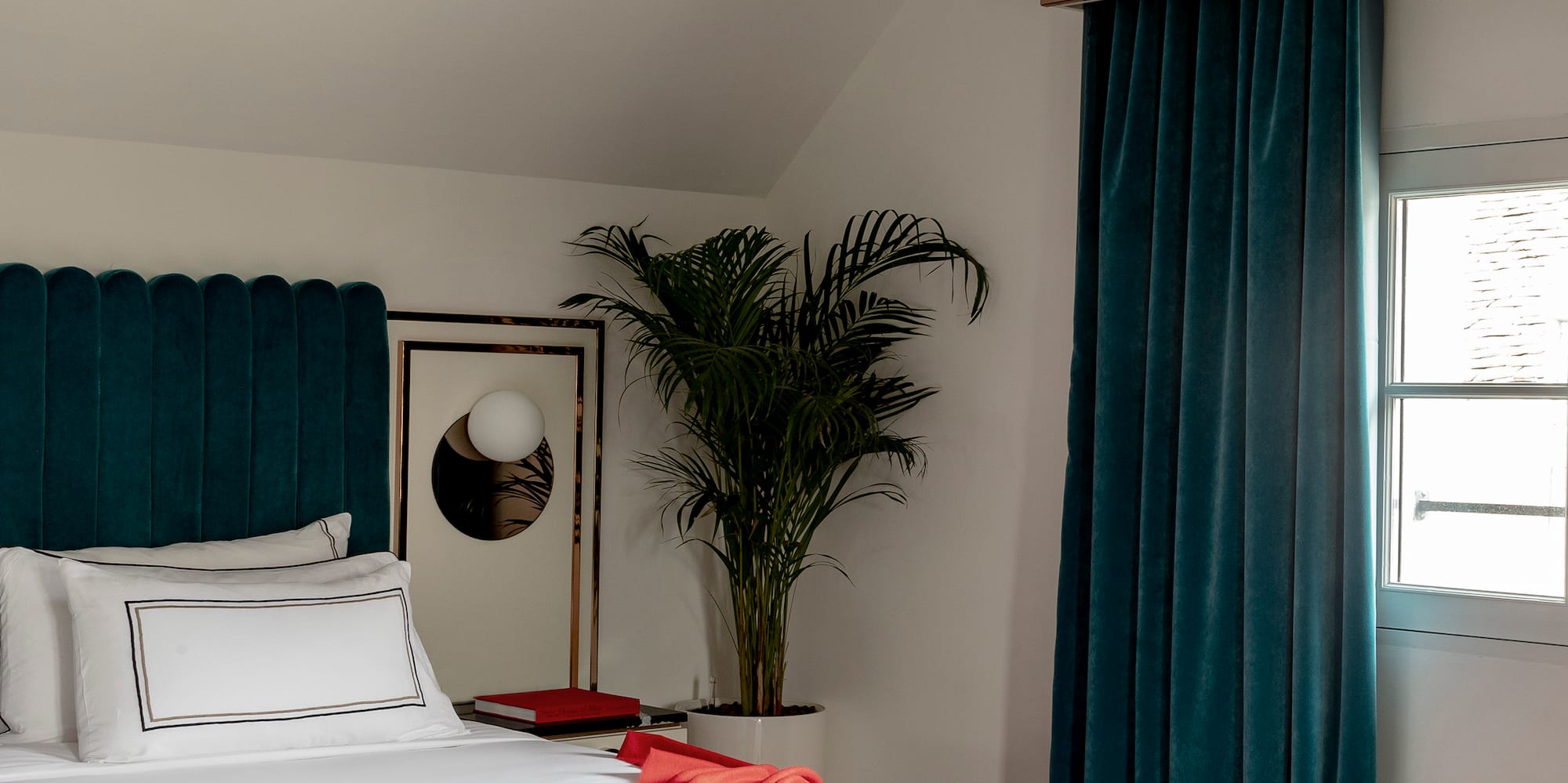 a bed with a red blanket and a palm tree in a room