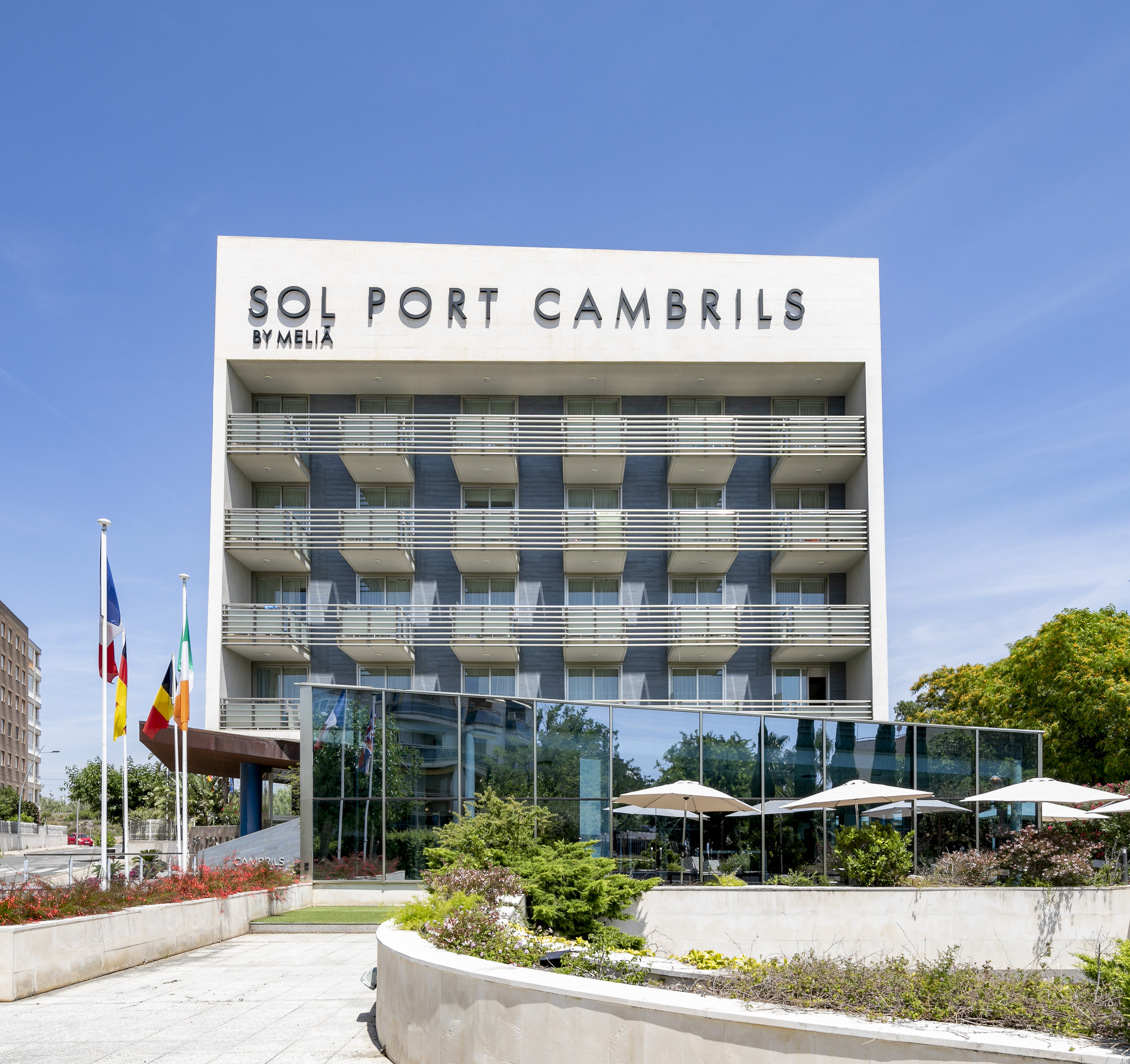 Sol Port Cambrils by Meliá hotel exterior with flags and balconies under blue sky.