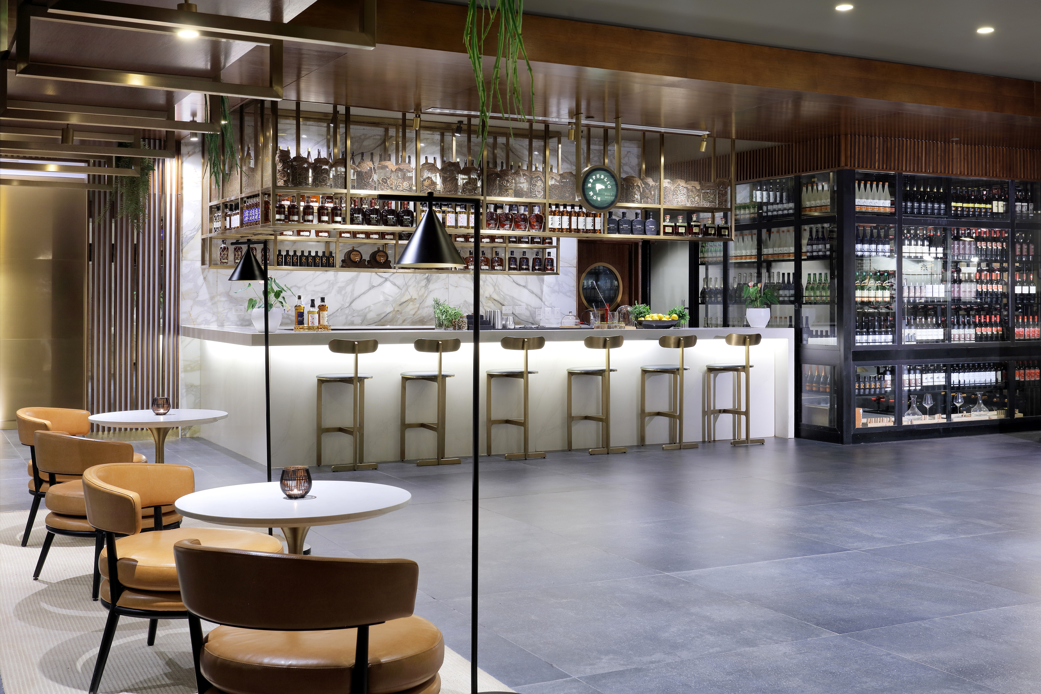 Elegant modern bar with marble counter, brass details, spirits, and wine bottles.