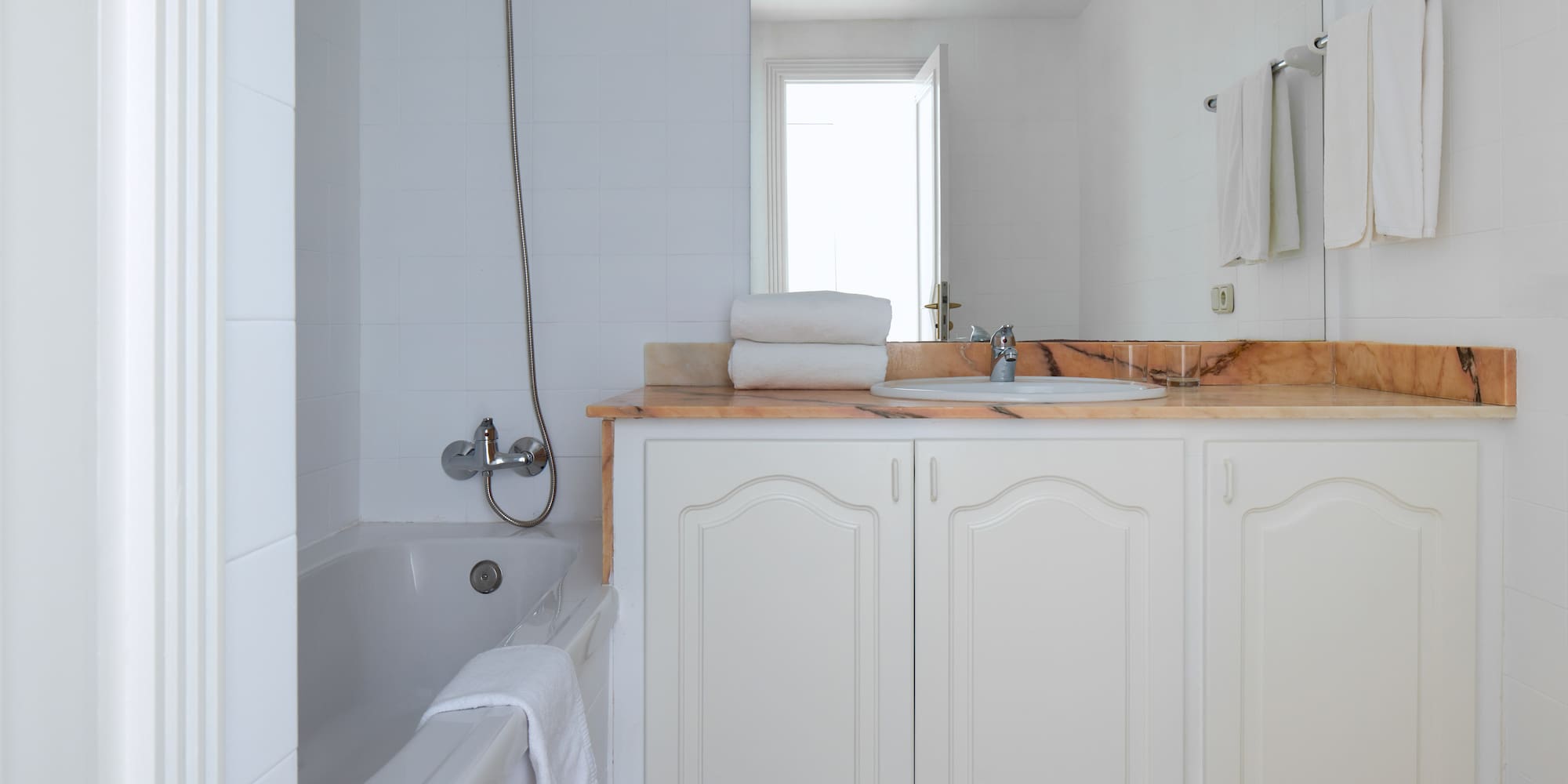 a bathroom with white cabinets and a bathtub